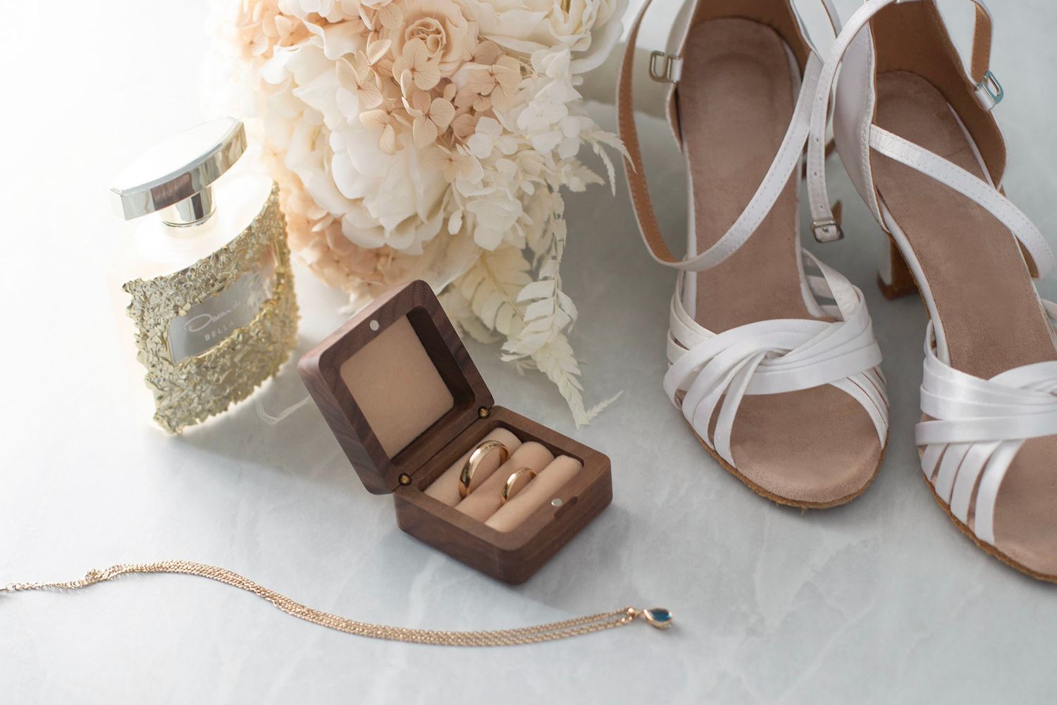 Wedding accessories including white shoes and decorative items arranged on light surface.