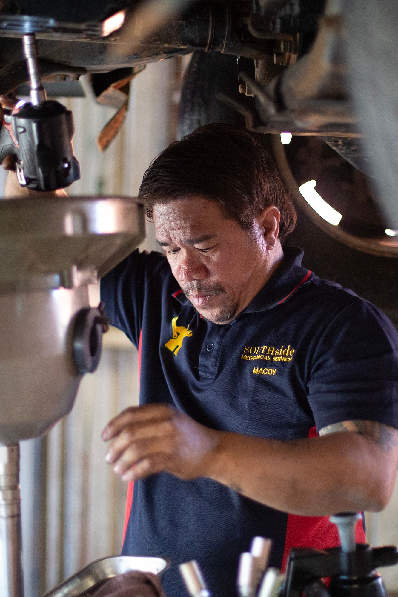 Automotive technician performing maintenance work in repair shop bay.