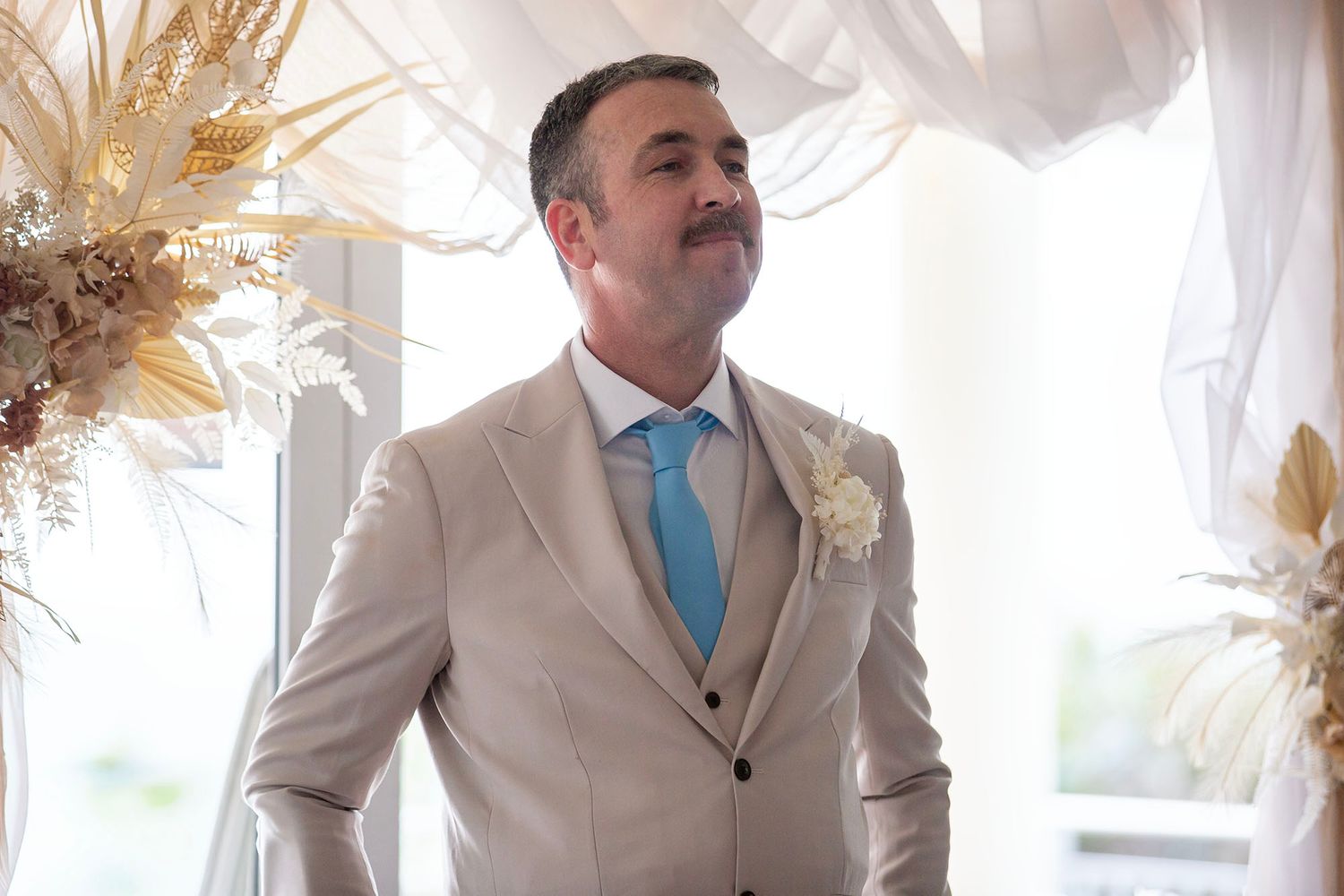 A wedding party poses in light colored formal attire with accents of blue.