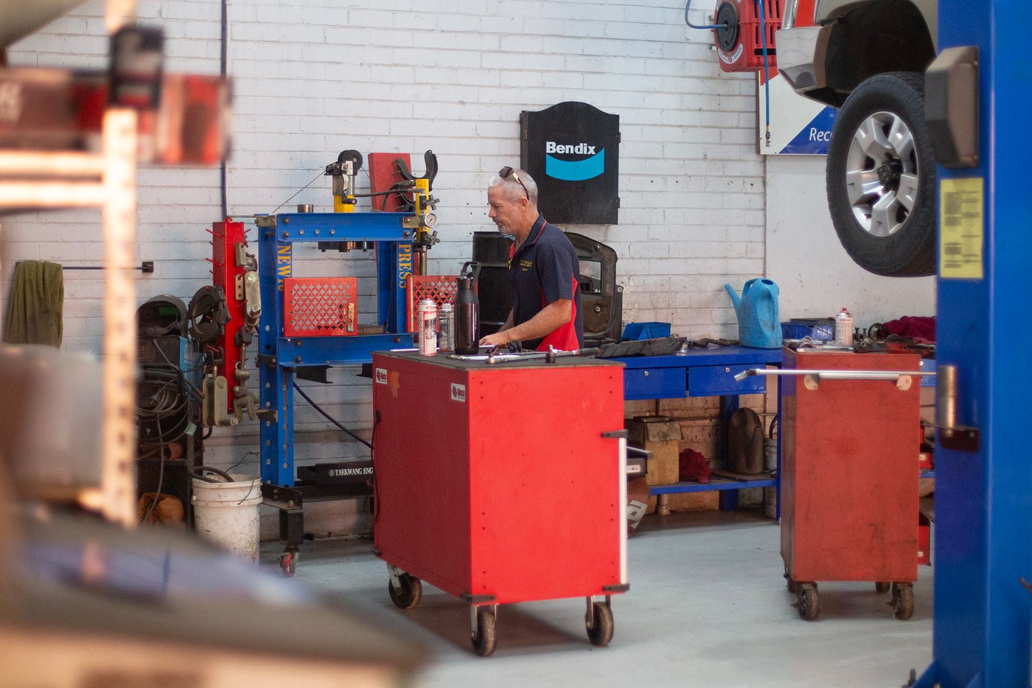 Clean modern auto repair garage with red tool cabinets and white walls.