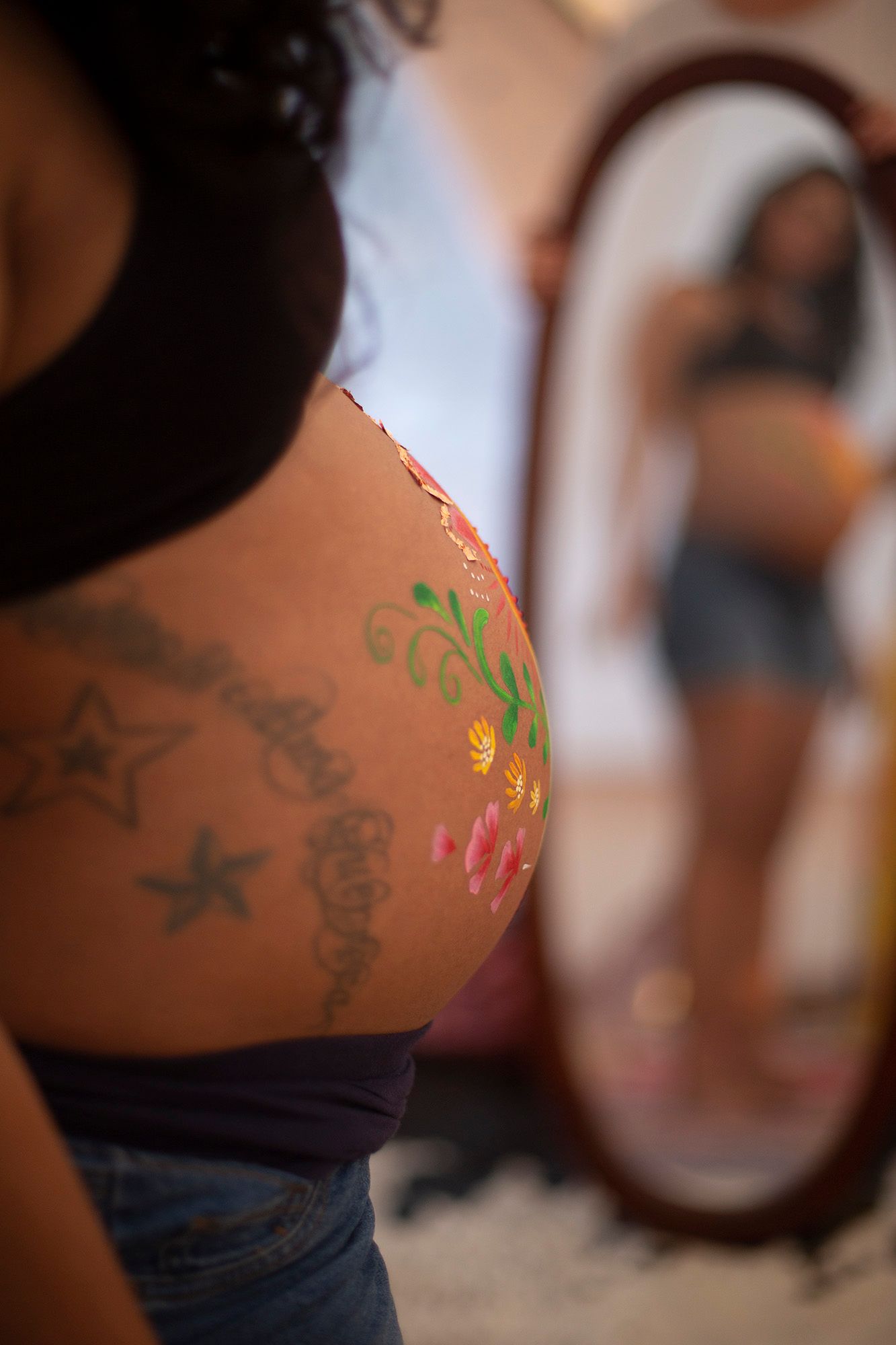 Close-up view of colorful body art and tattoos on skin in warm lighting.