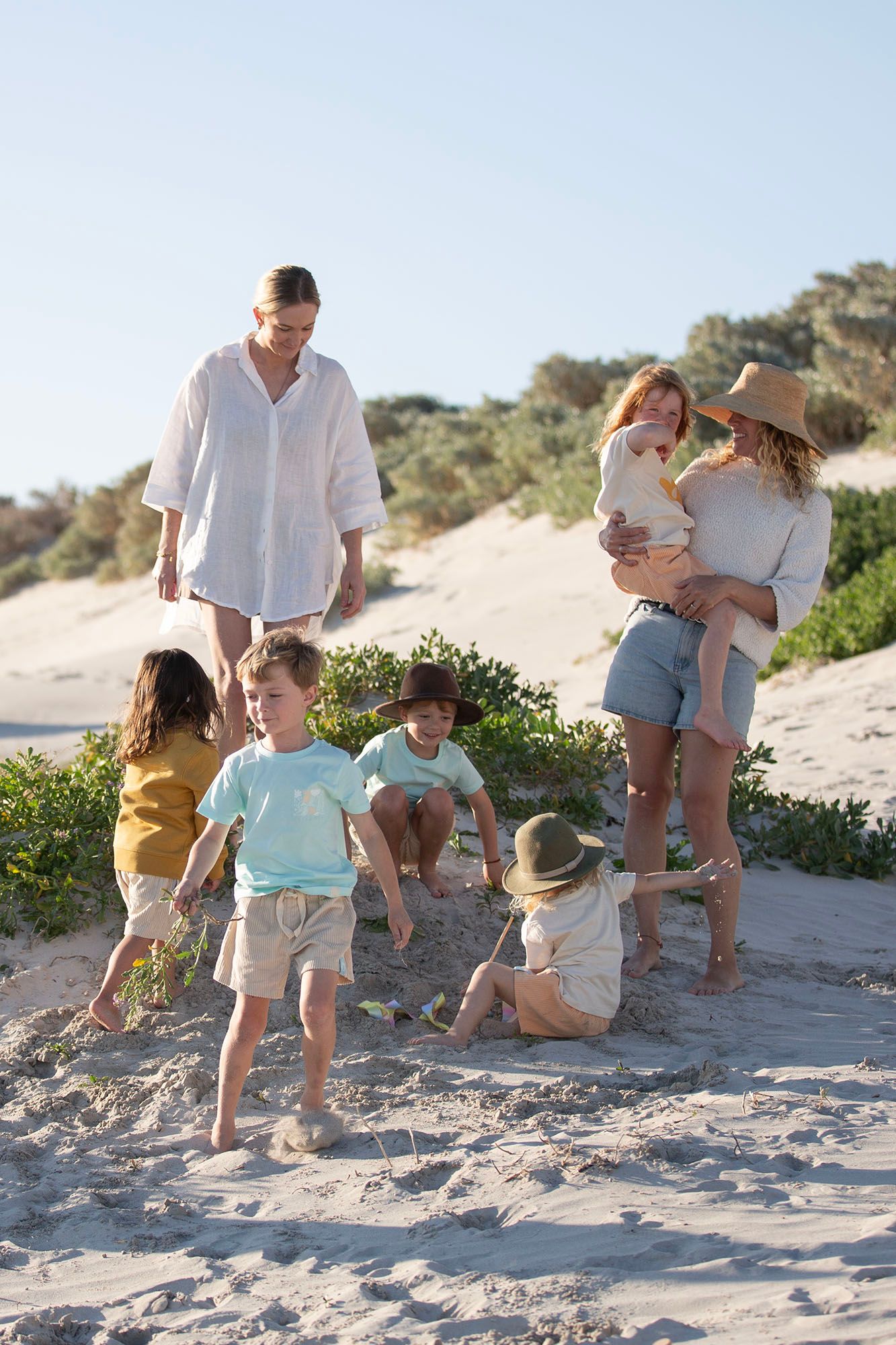 Family enjoying a playful moment on sandy dunes near the ocean.