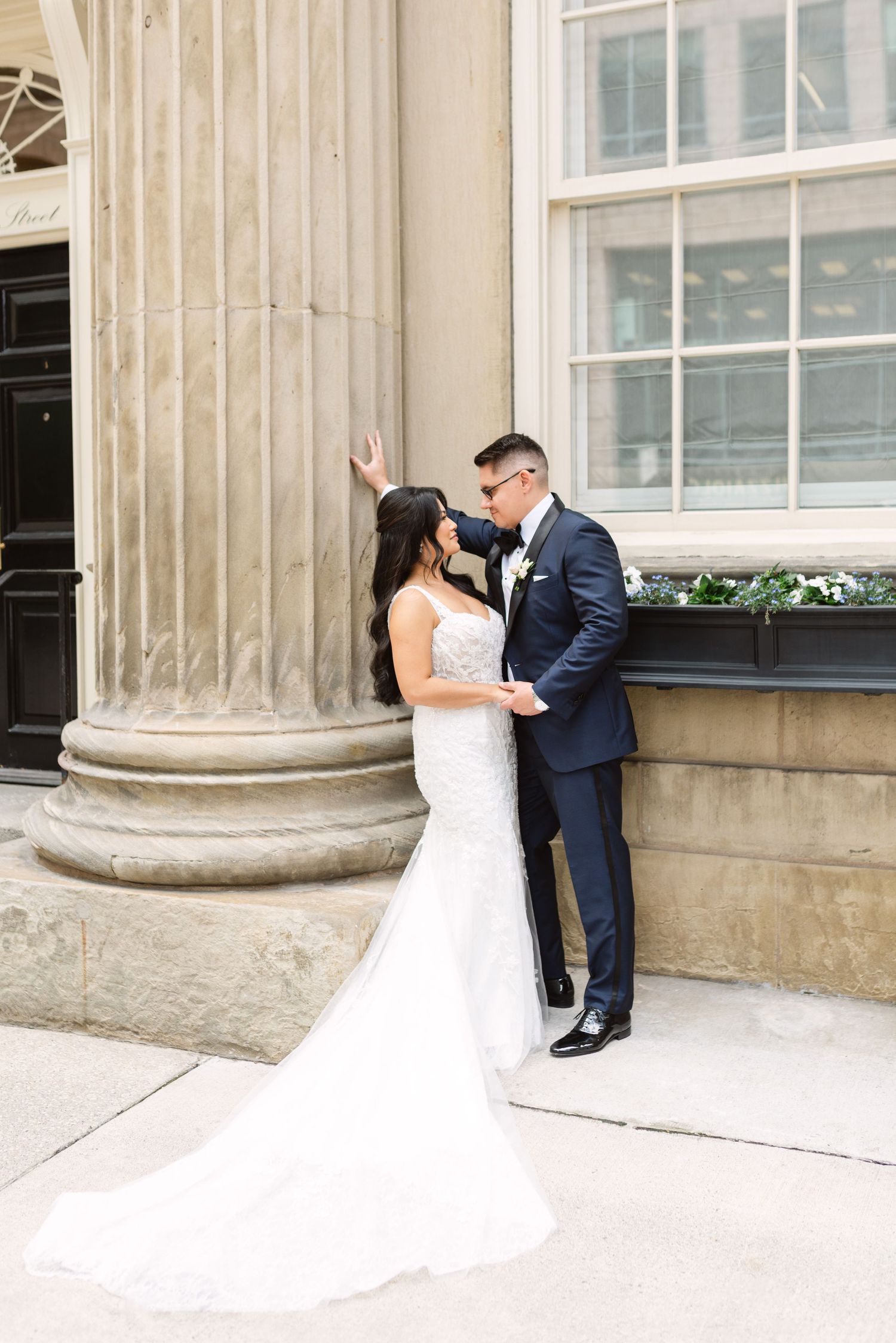 Wedding couple shares intimate moments against a classical stone column backdrop.