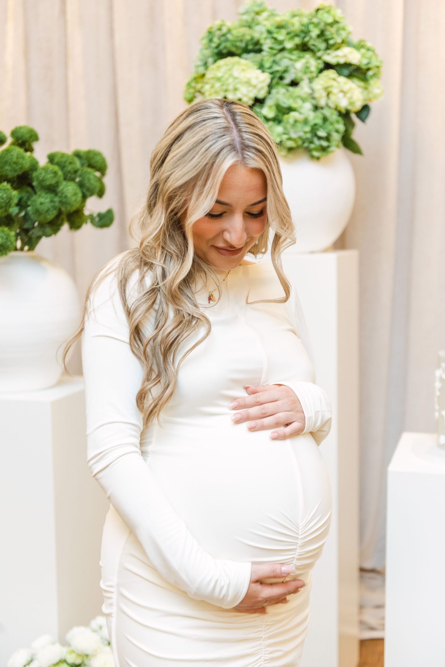 Maternity celebration setup with white dress and green floral decorations.