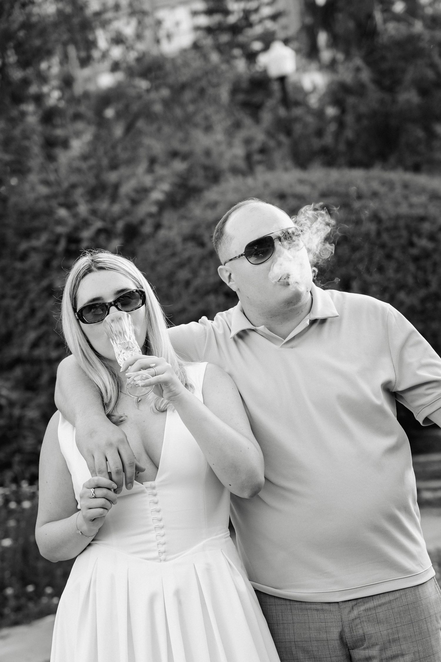 Black and white photo of a couple sharing drinks through straws outdoors.