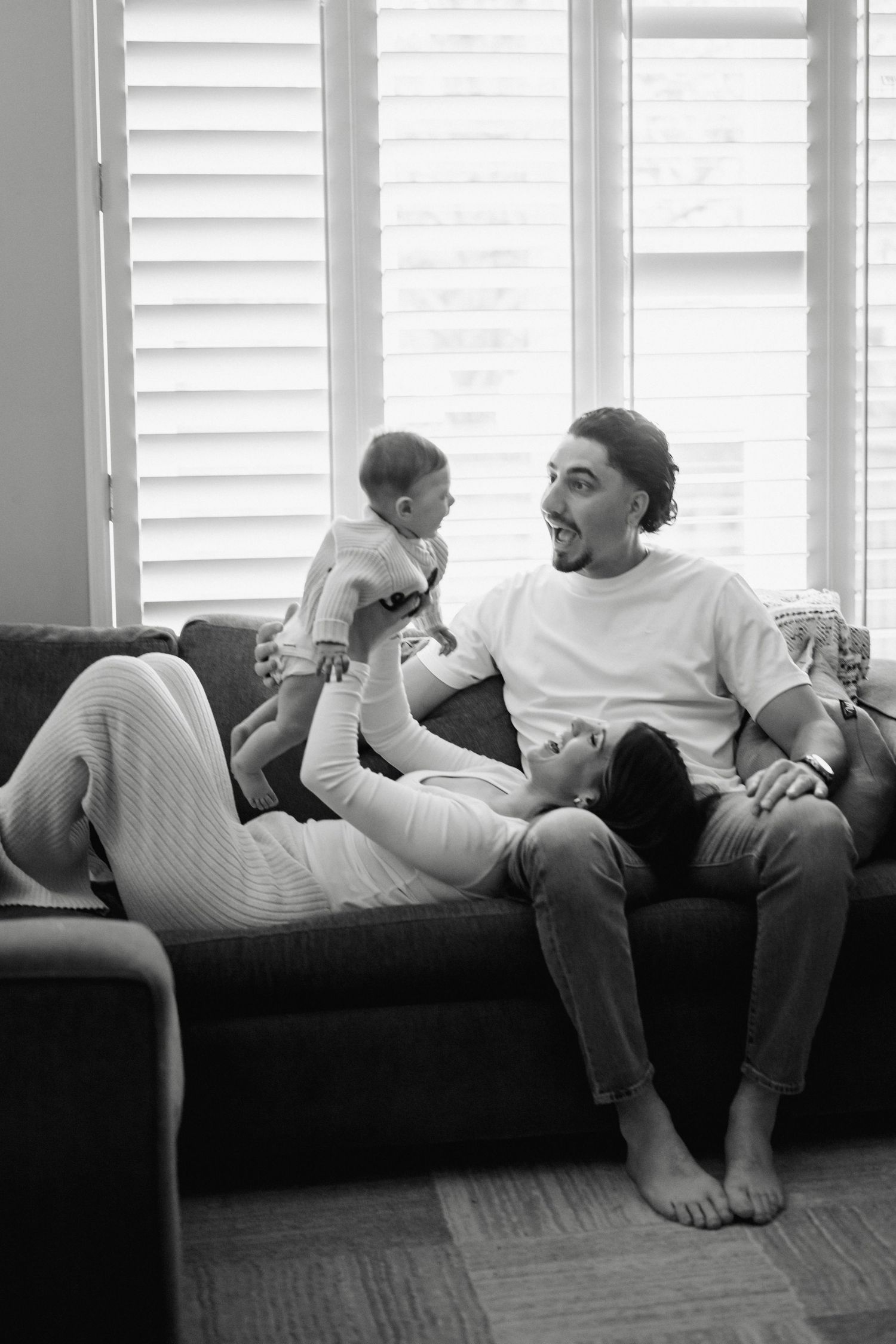 A black and white photo series showing a couple relaxing together on a window seat with white shutters.