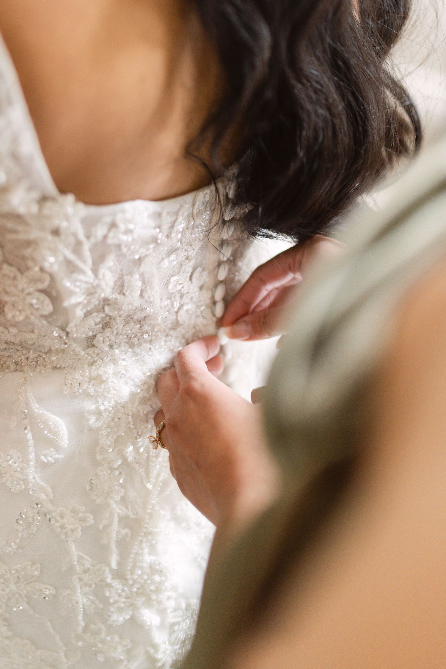 Close-up detail shots of delicate white lace and beading on a wedding dress.