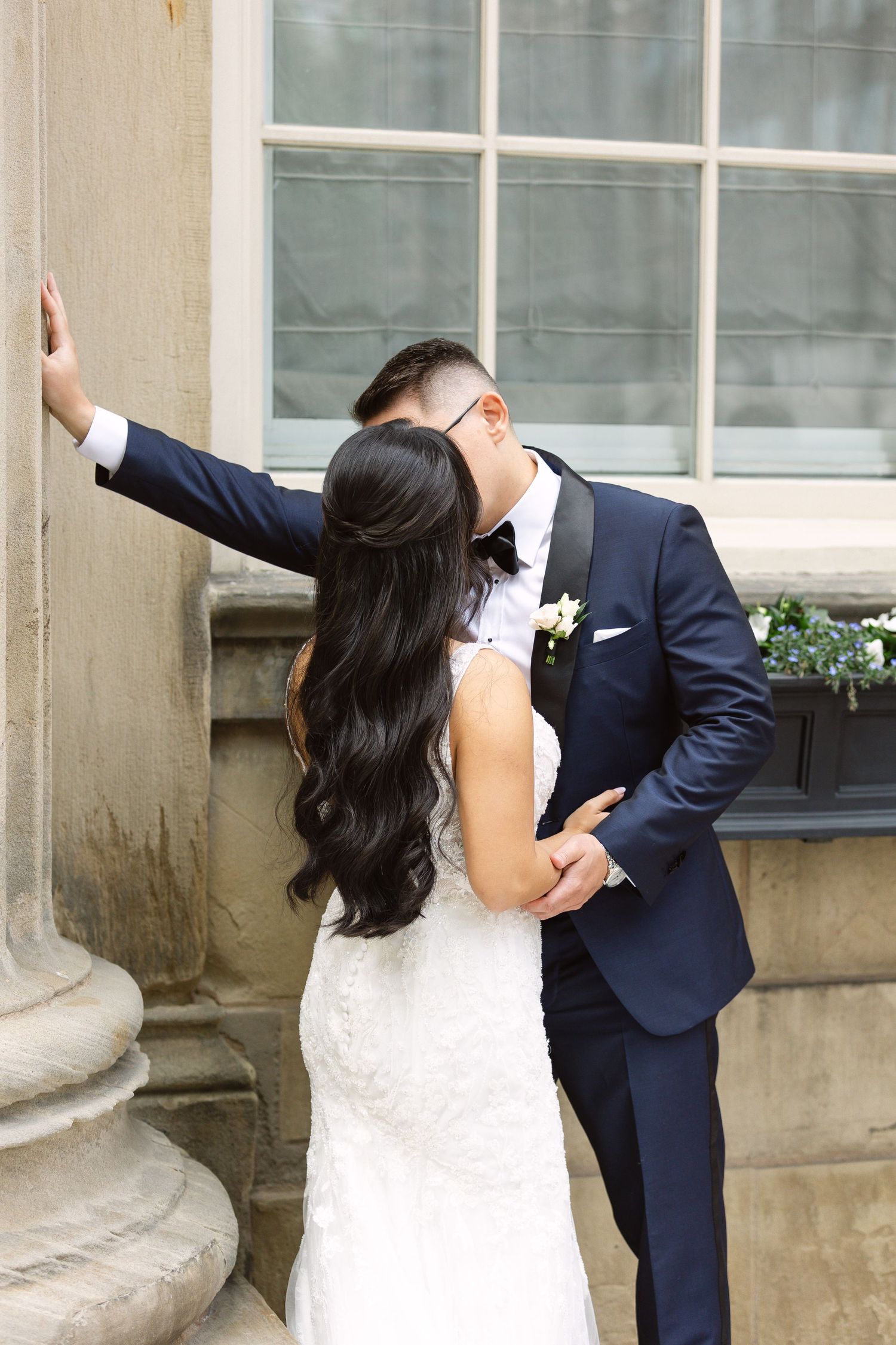 Bride and groom share playful dance moves against architectural backdrop.