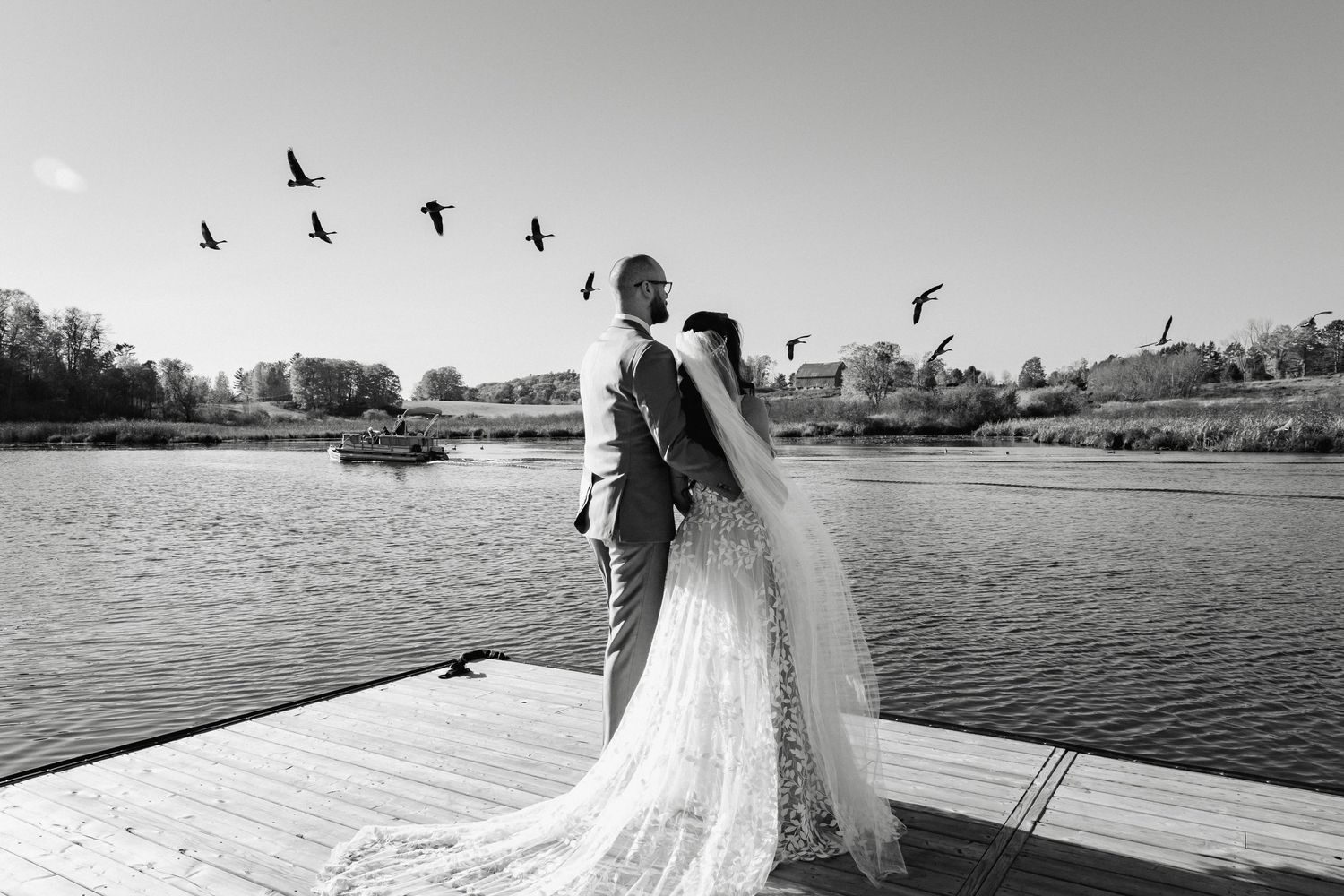 Wedding photos at a waterfront location with birds flying overhead.