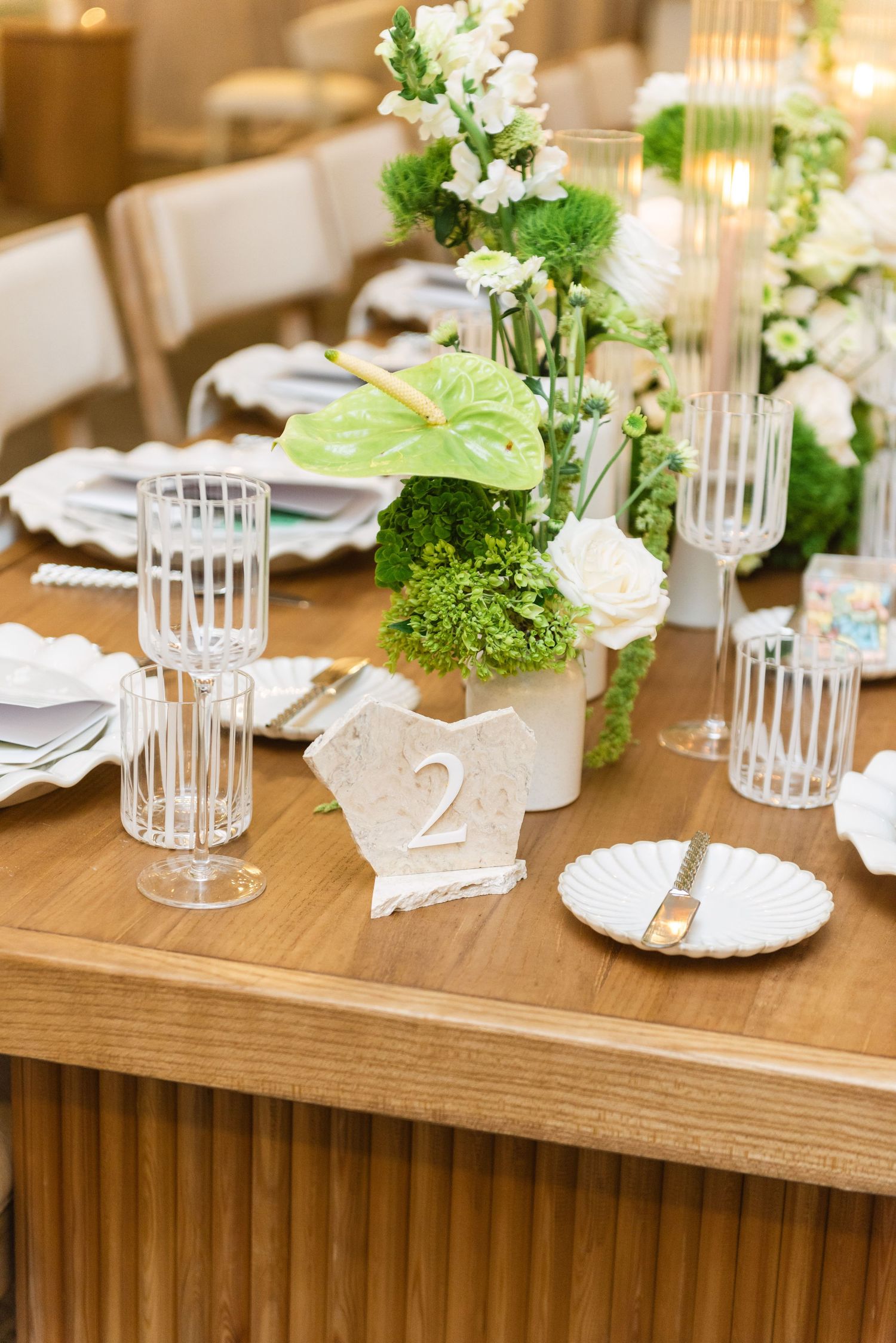 Wedding table setting with white flowers, crystal glassware, and table number two.