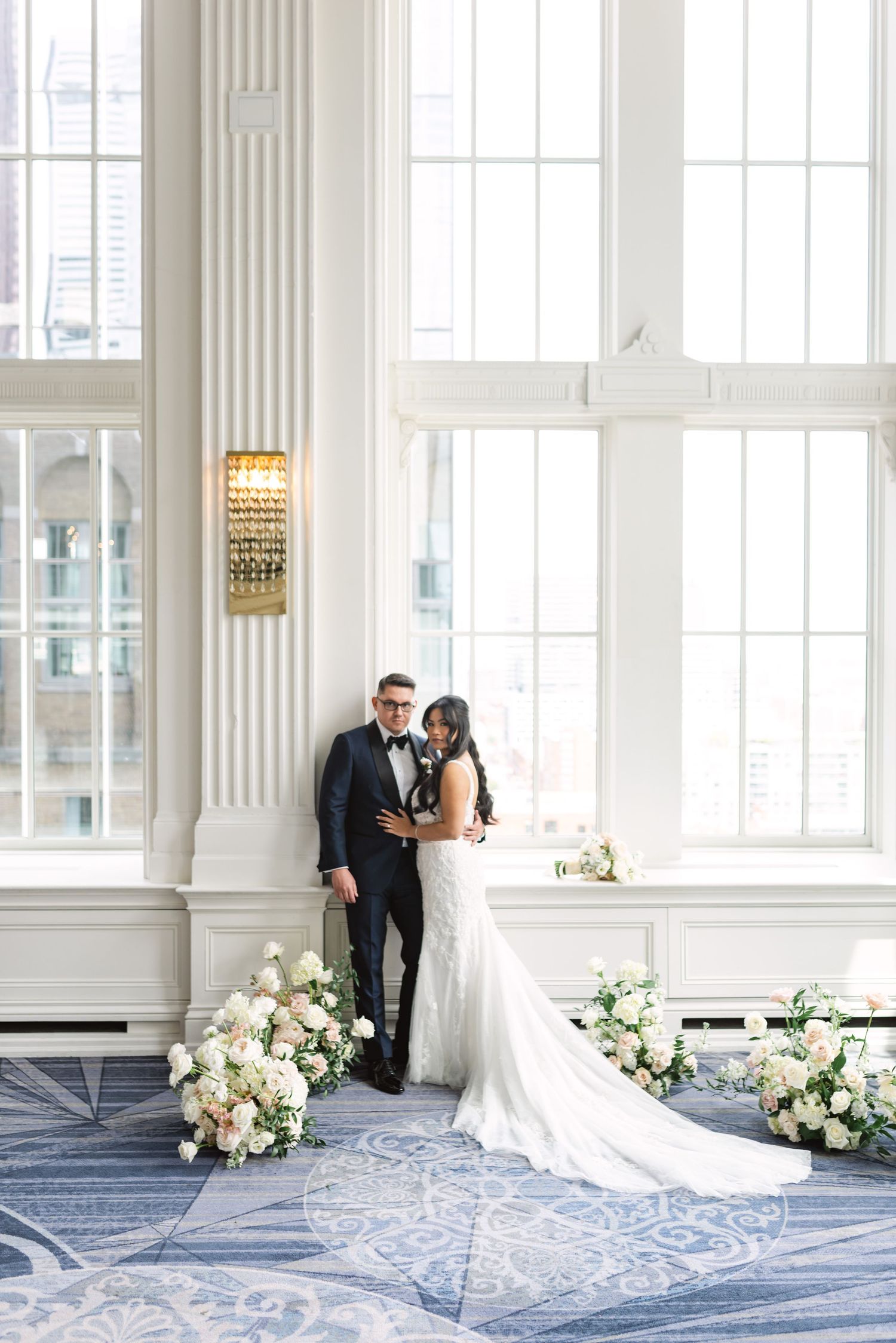 Elegant wedding portraits in a bright room with white columns and floral arrangements.