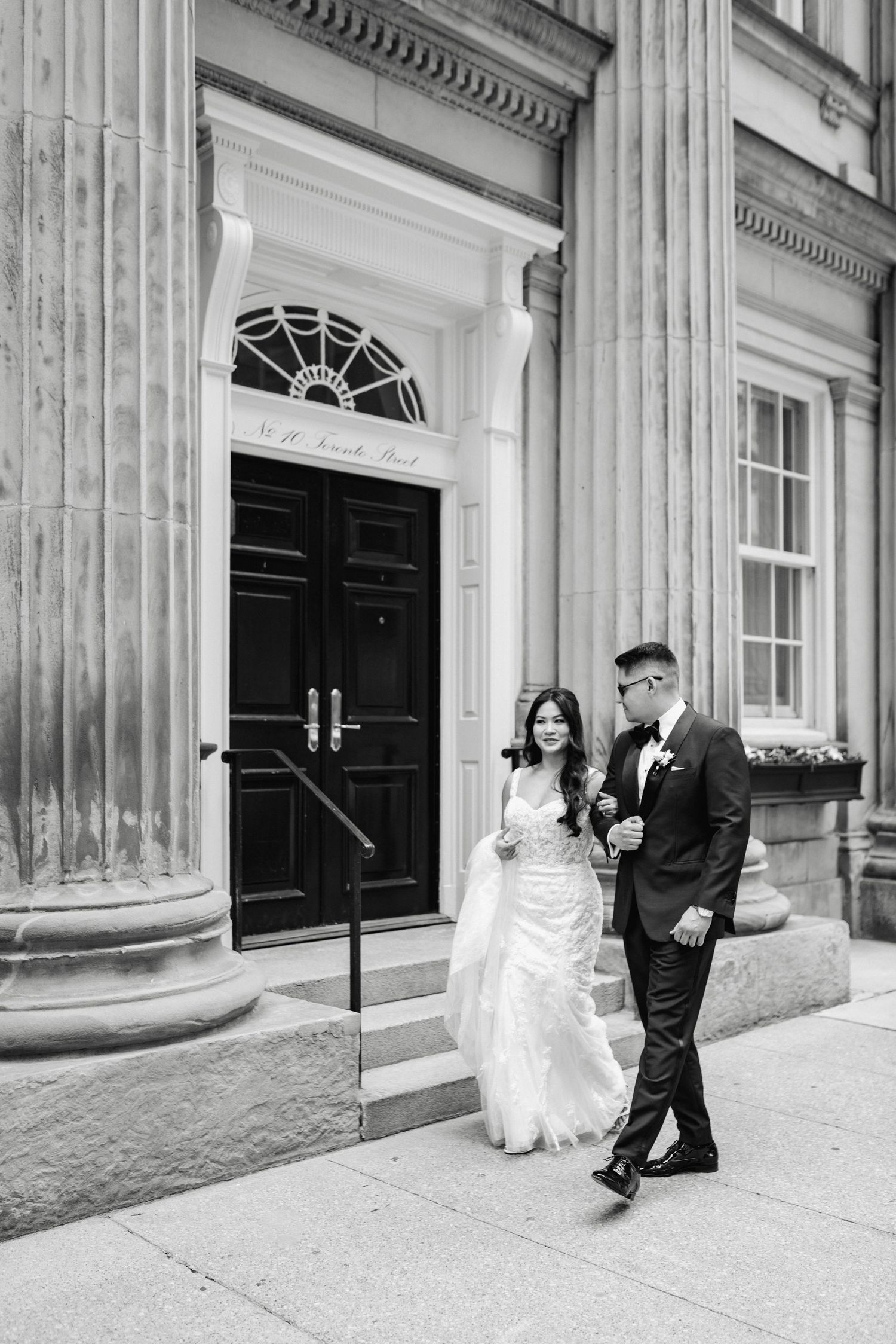 Newlyweds sharing a romantic moment outside a historic building with elegant columns.