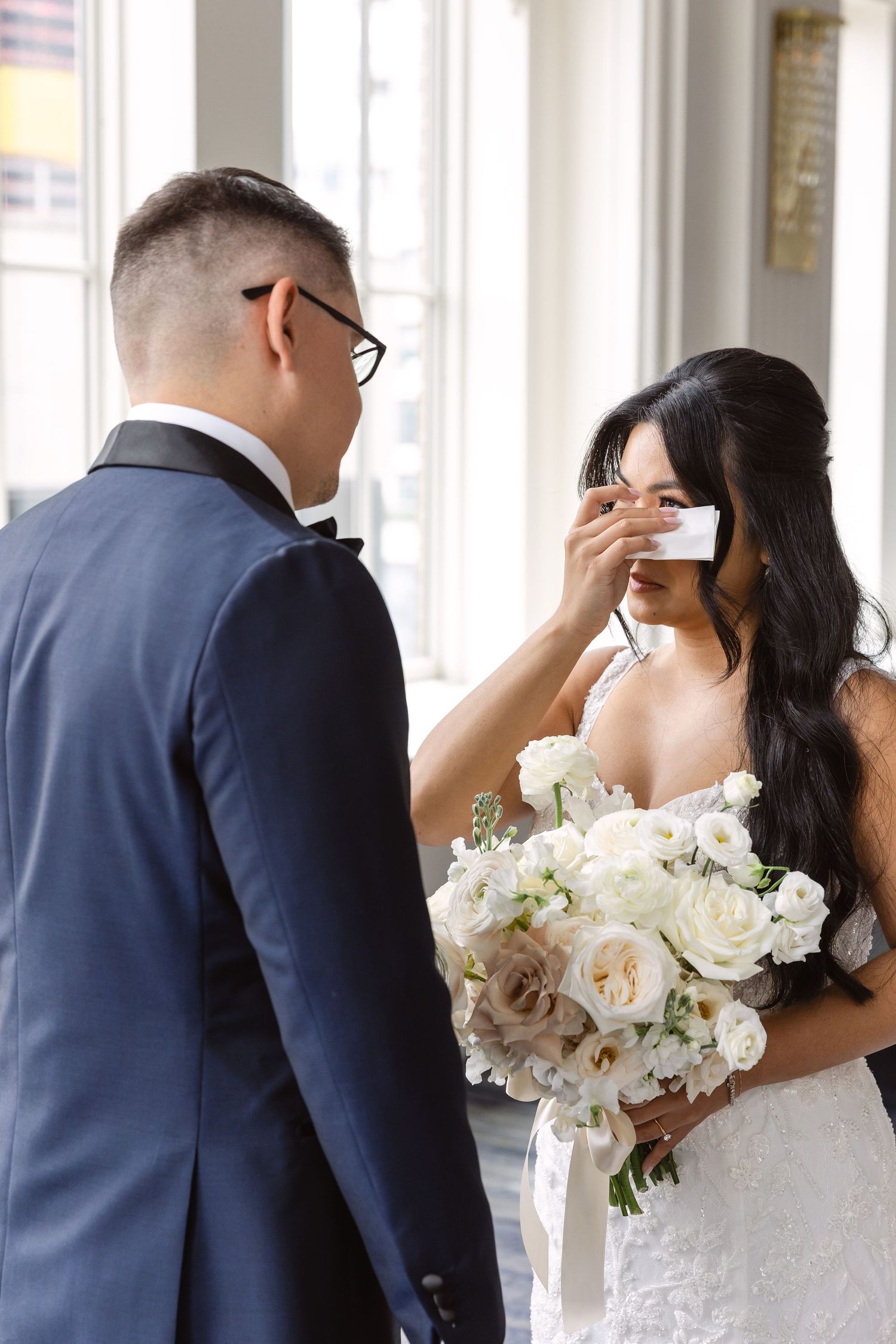 Intimate wedding moment photographed in a bright, classic ballroom setting.