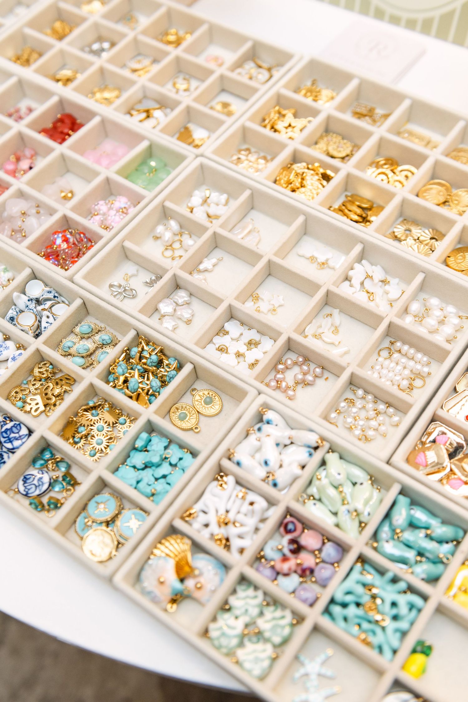 Organized display tray of colorful jewelry pieces and accessories in small compartments.
