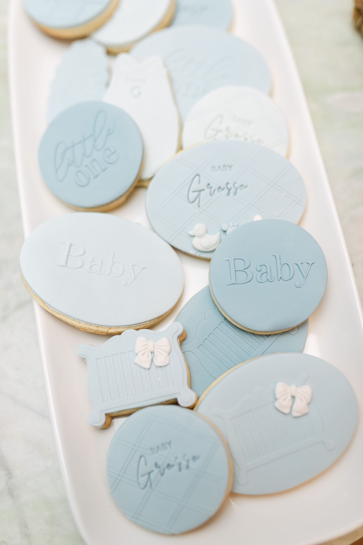 Delicate light blue and white sugar cookies with butterfly decorations arranged on a white surface.