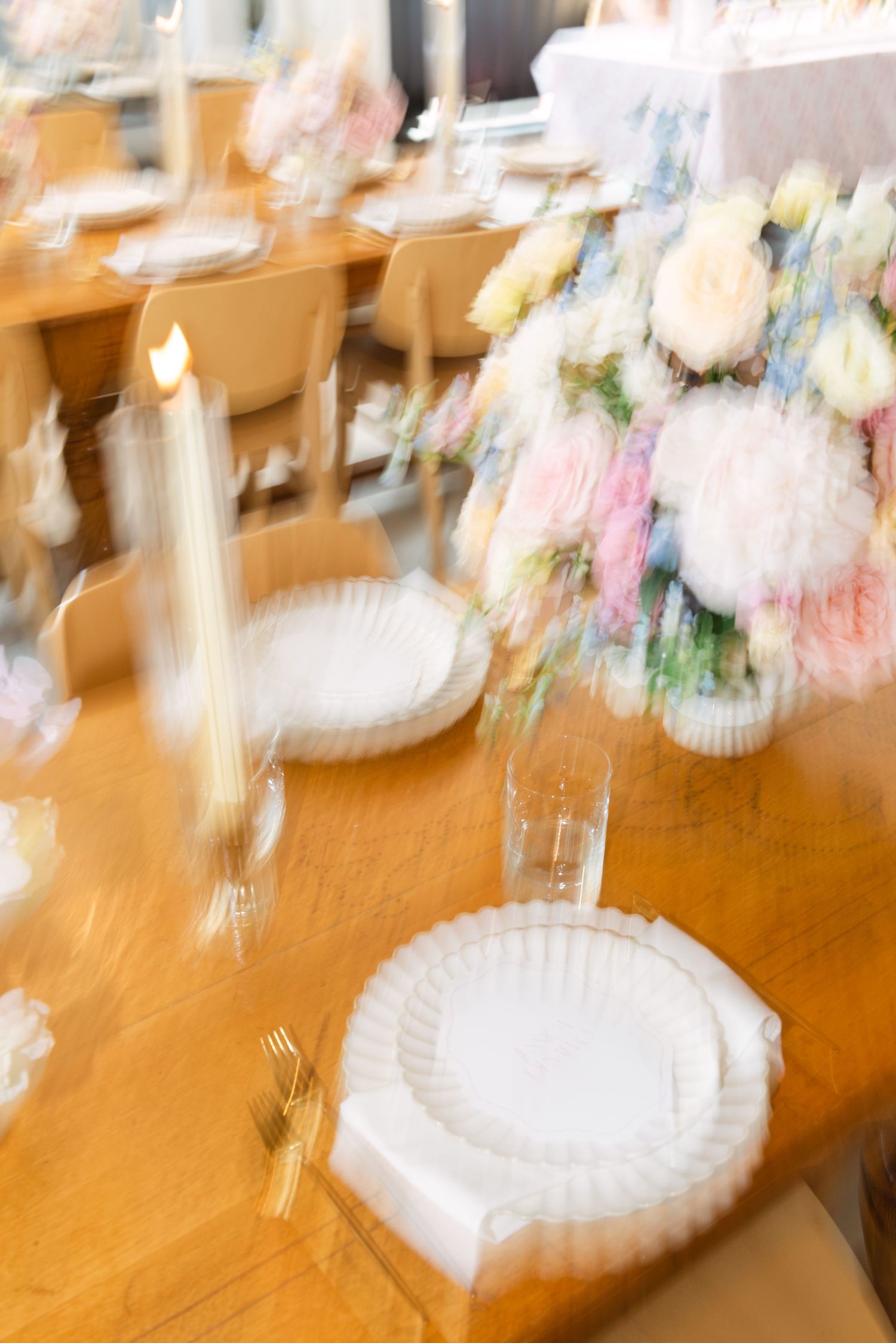 Artistic blurred view of elegant table settings with white plates and floral decorations.