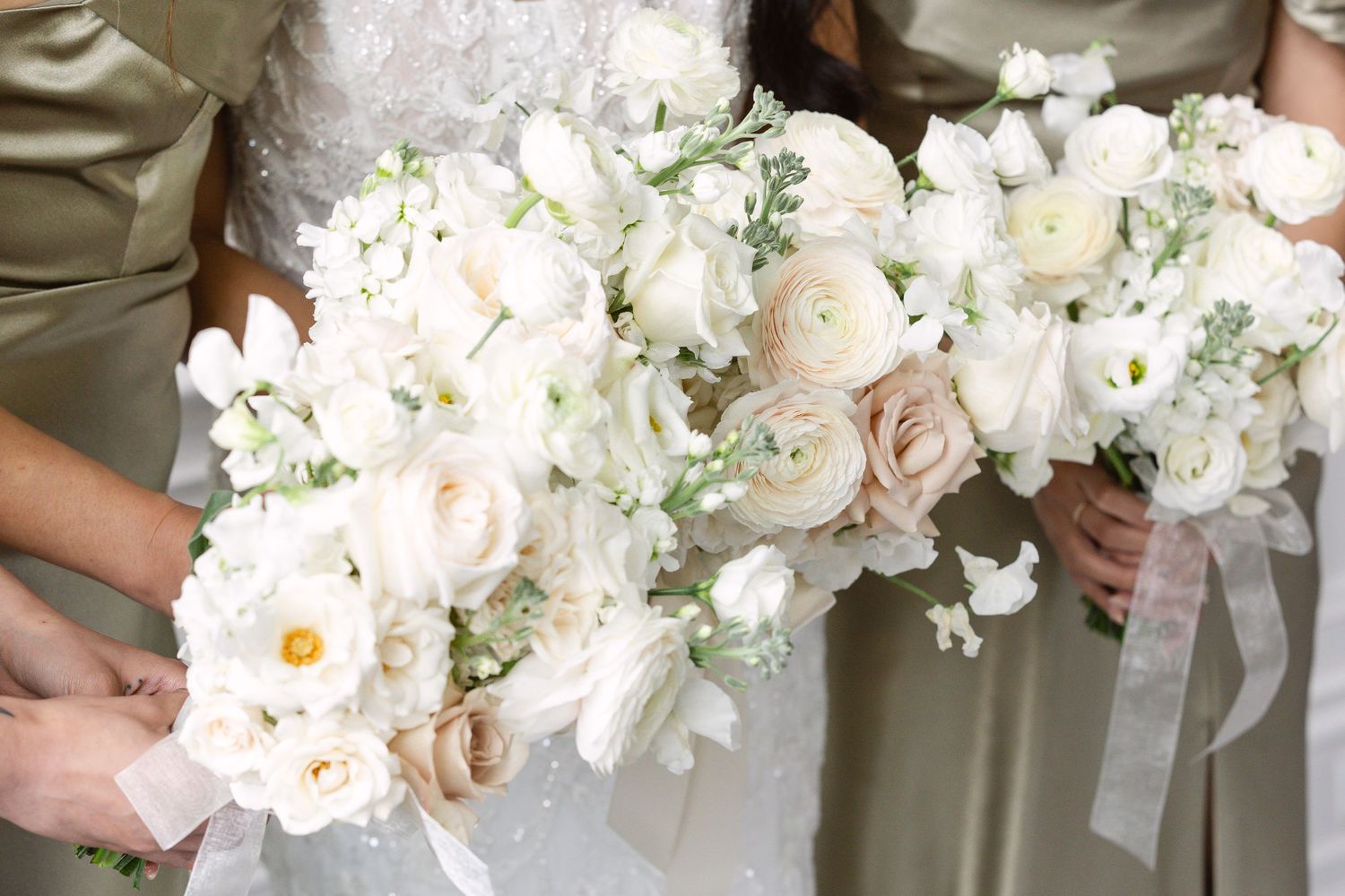 Close-up of luxurious white and blush wedding bouquets with roses and delicate ribbons.