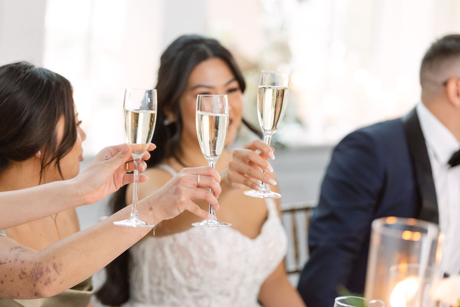 Wedding guests raising champagne glasses for a celebratory toast at an elegant reception.