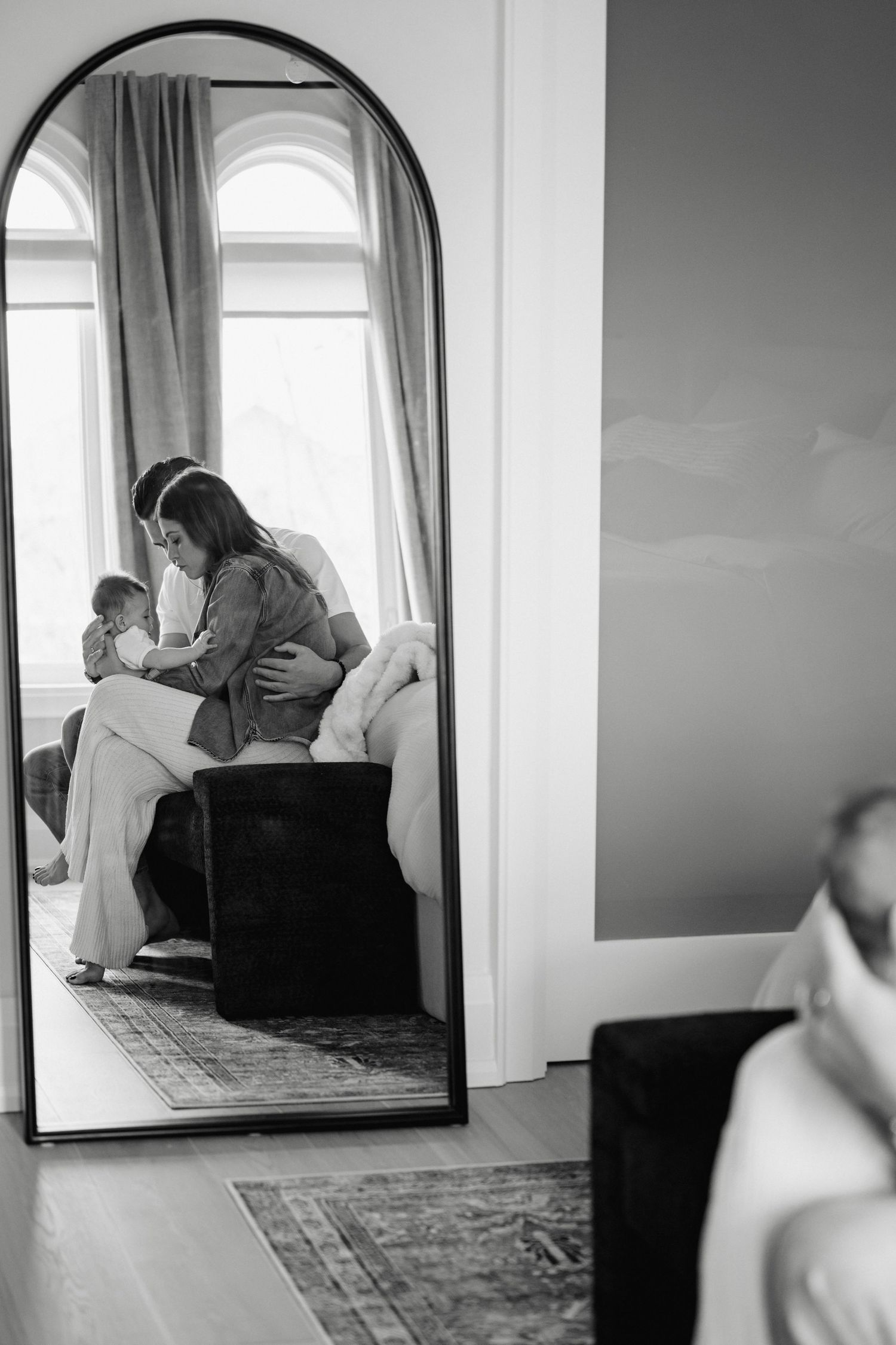A series of black and white photographs showing a person reflected in a mirror within a minimalist interior space.