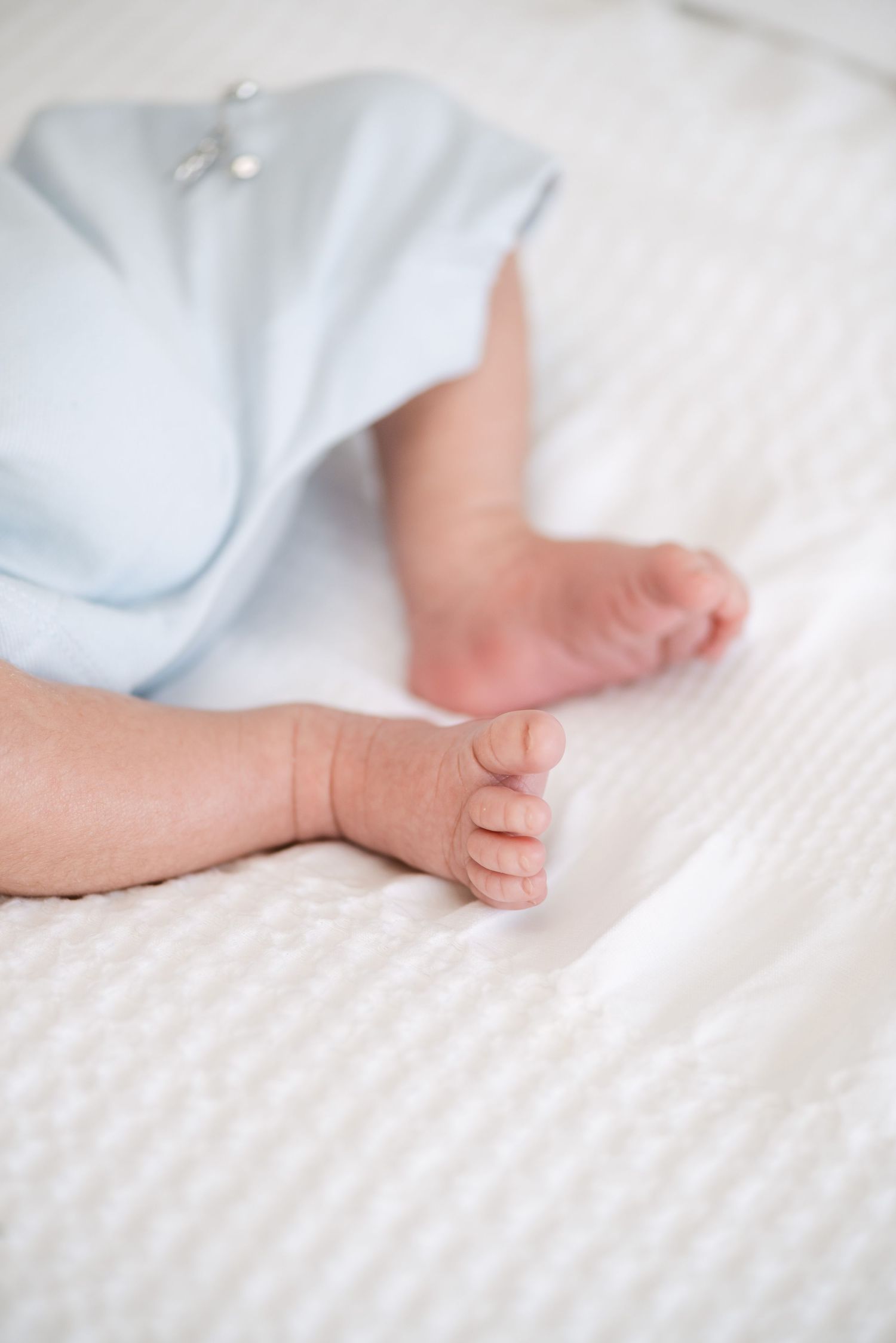 Close-up of baby feet on white textured bedding.