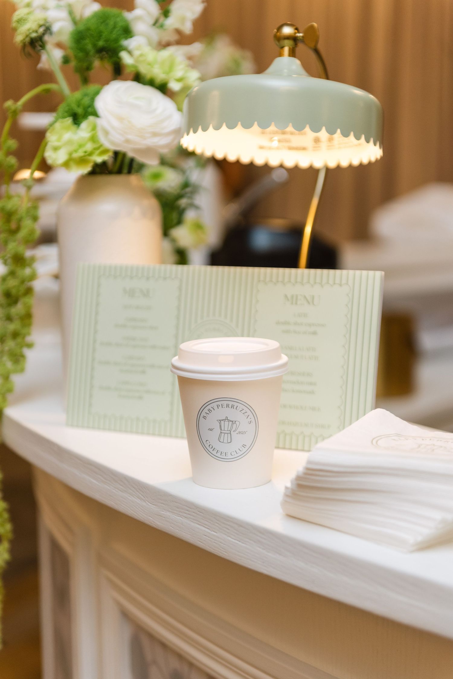 White branded coffee cups and menus displayed on shelving with soft lighting.