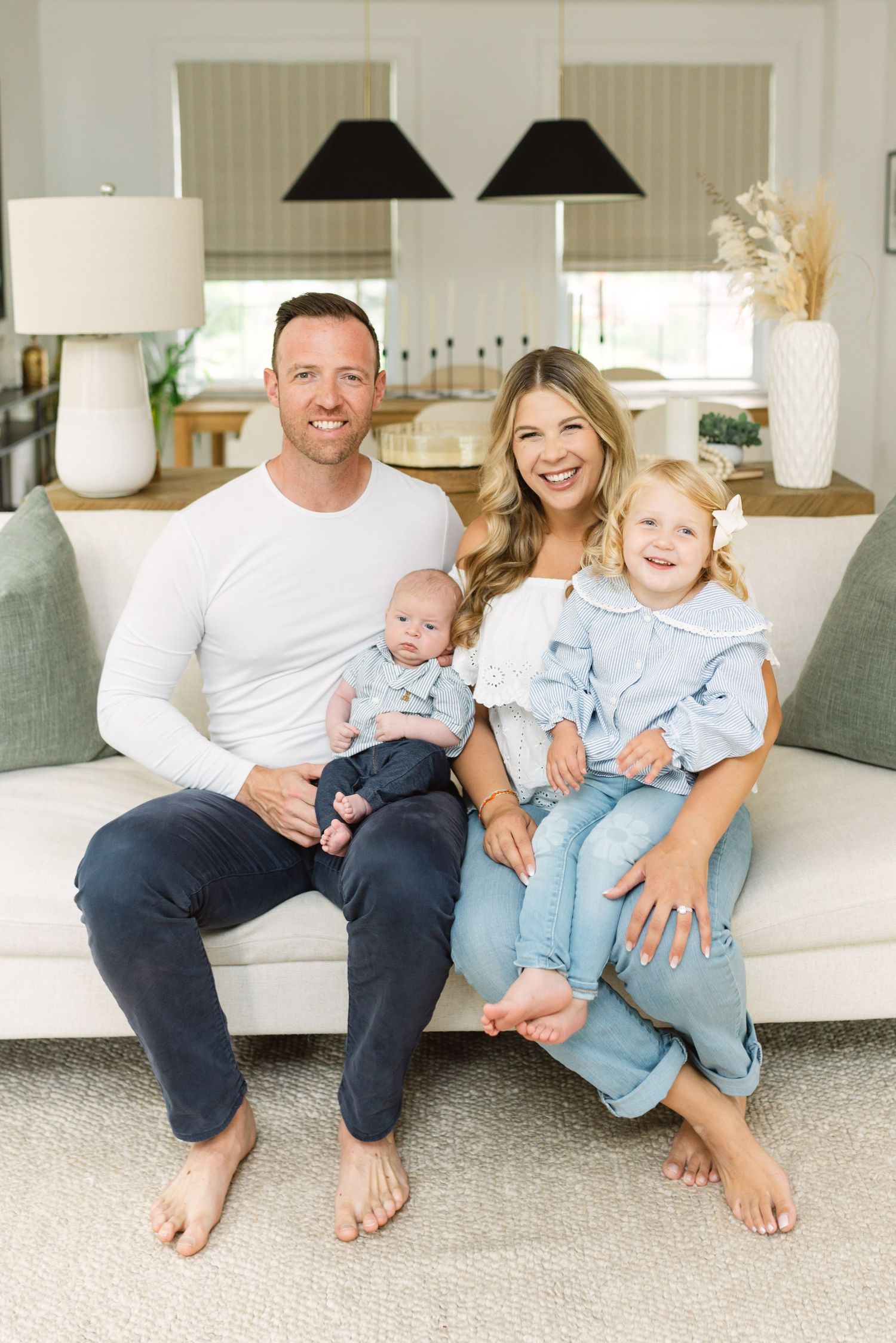 Casual family portrait series on white couch in matching blue and white clothing.