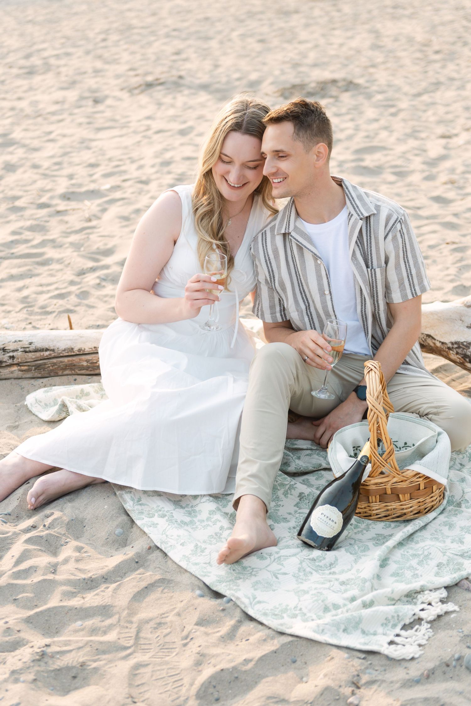 Romantic beach picnic setup with couple sharing food on a blanket at sunset.