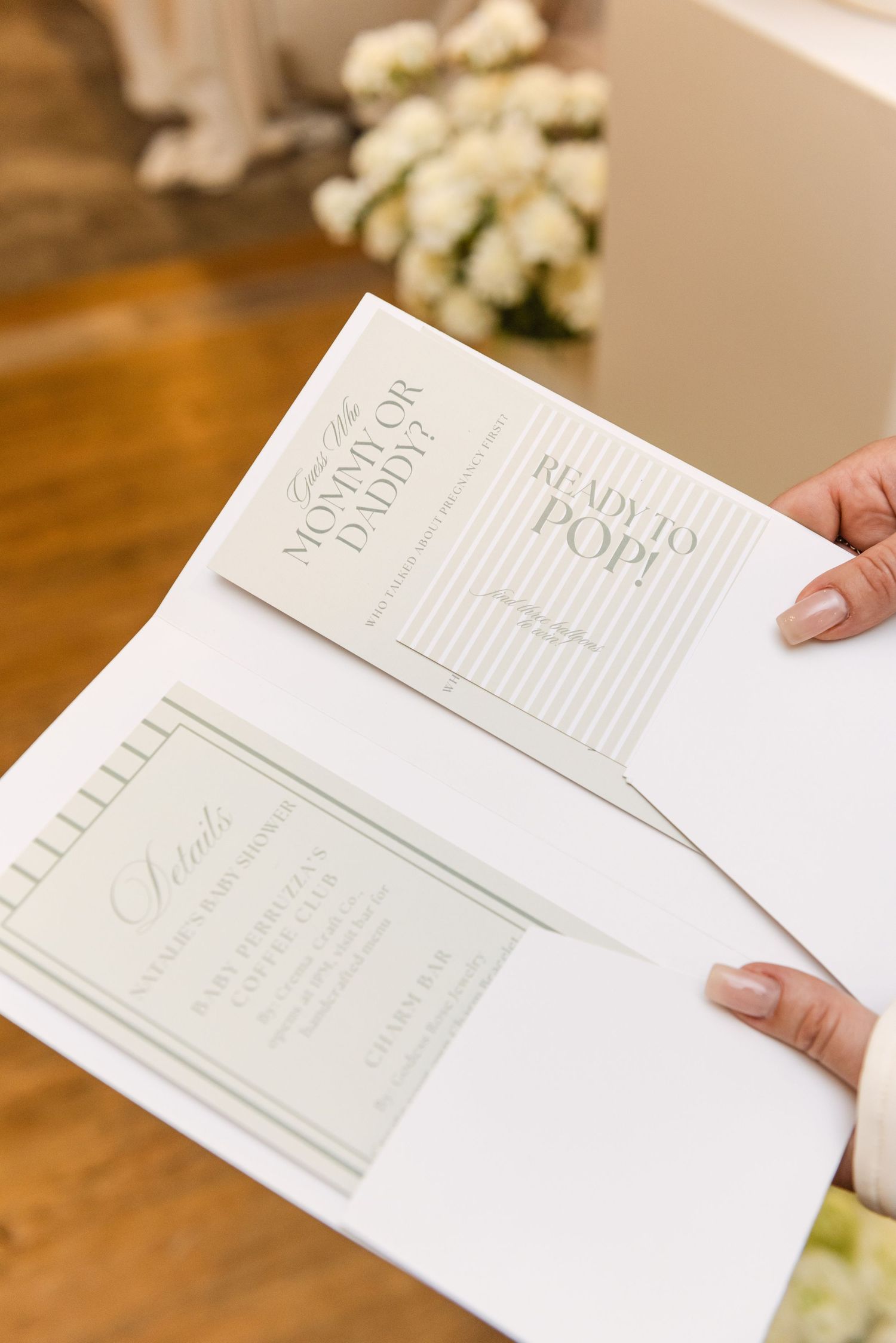 Wedding invitation suite in soft gray and white tones being held open to display design.
