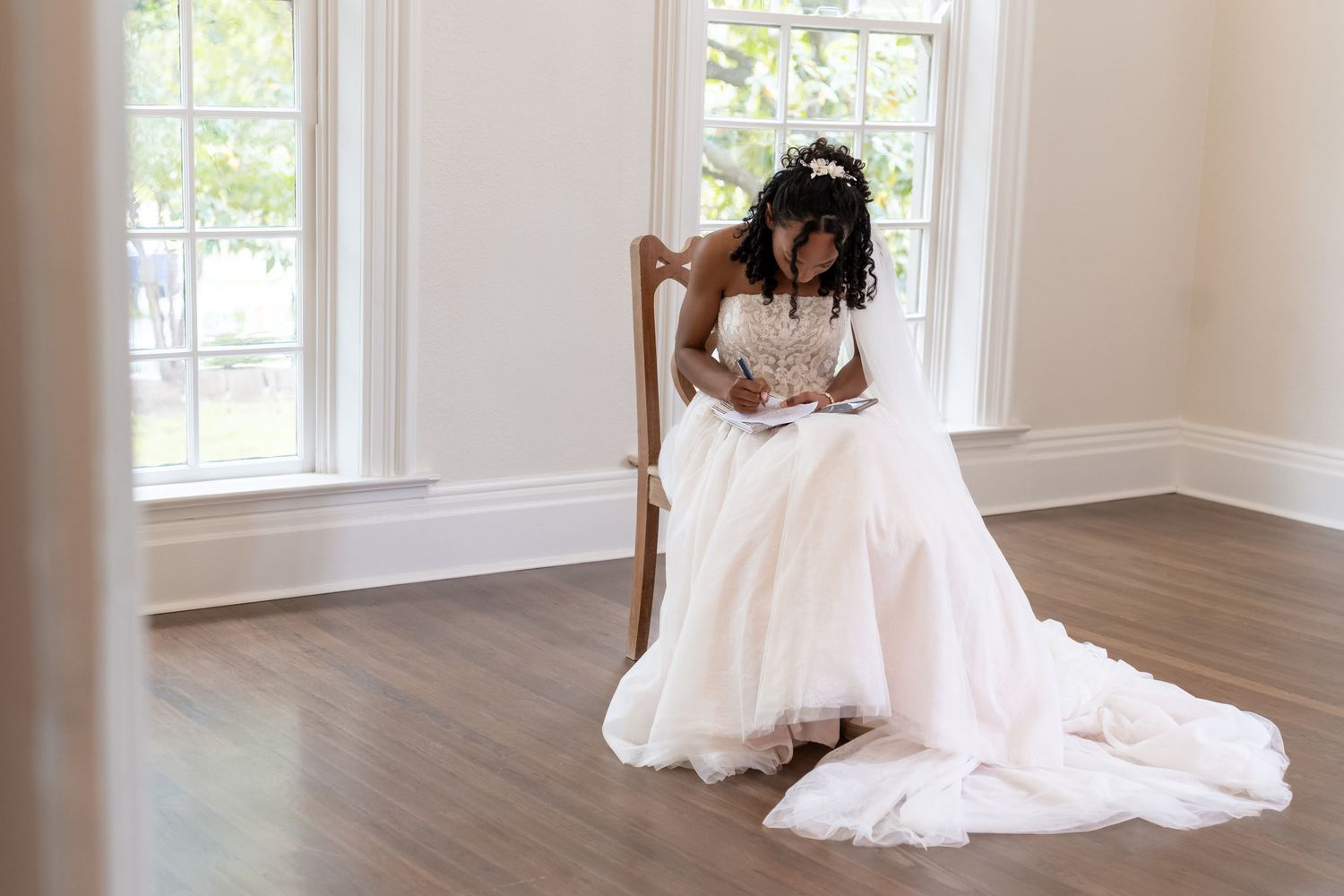 A wedding dress fitting in a bright interior space with hardwood floors.
