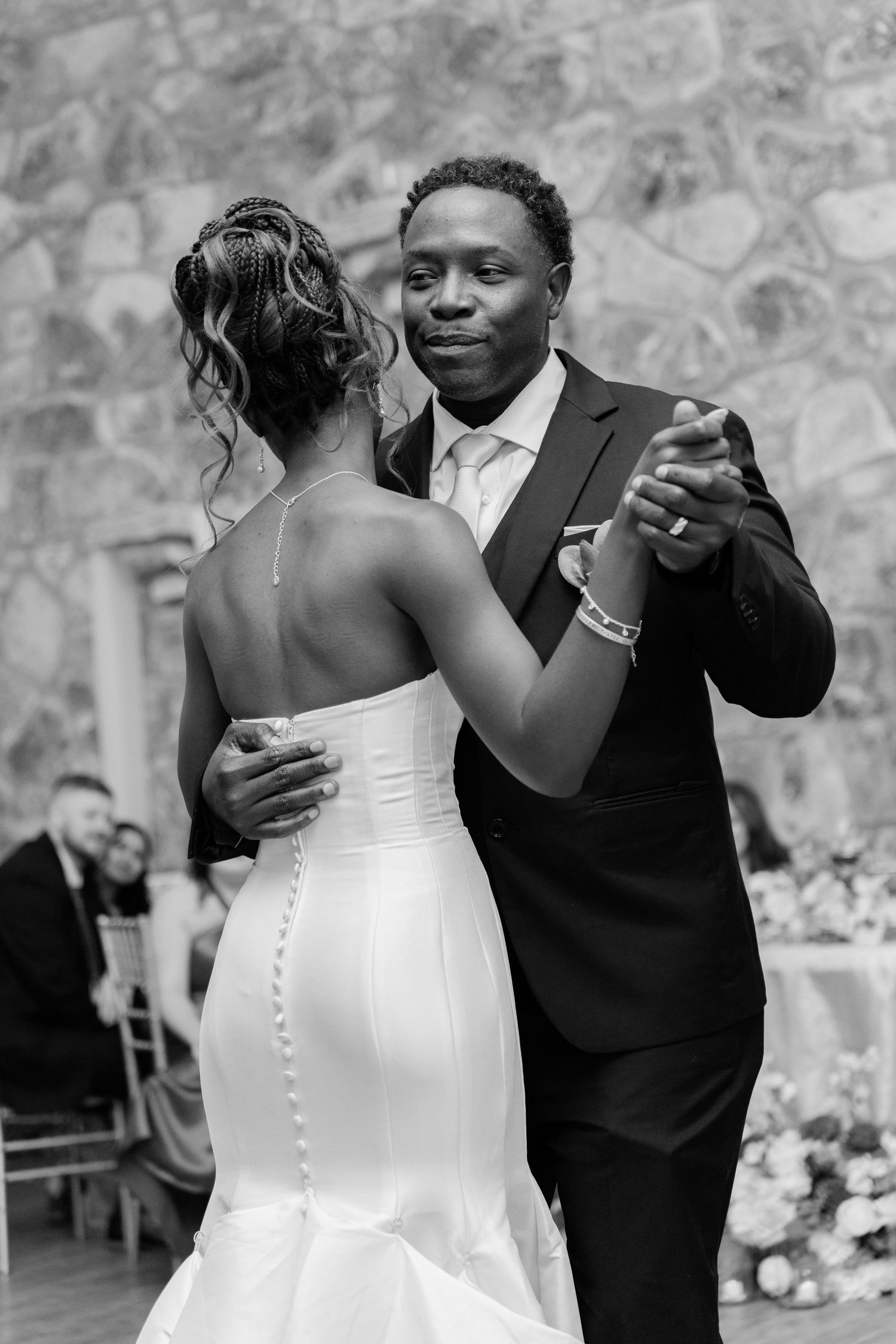 A couple shares their first dance at their wedding reception, with the bride in a white gown and groom in a dark suit.