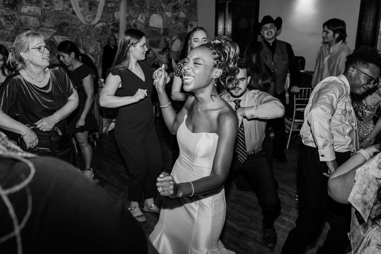 Black and white photo of people dancing and celebrating at a lively party or wedding reception.
