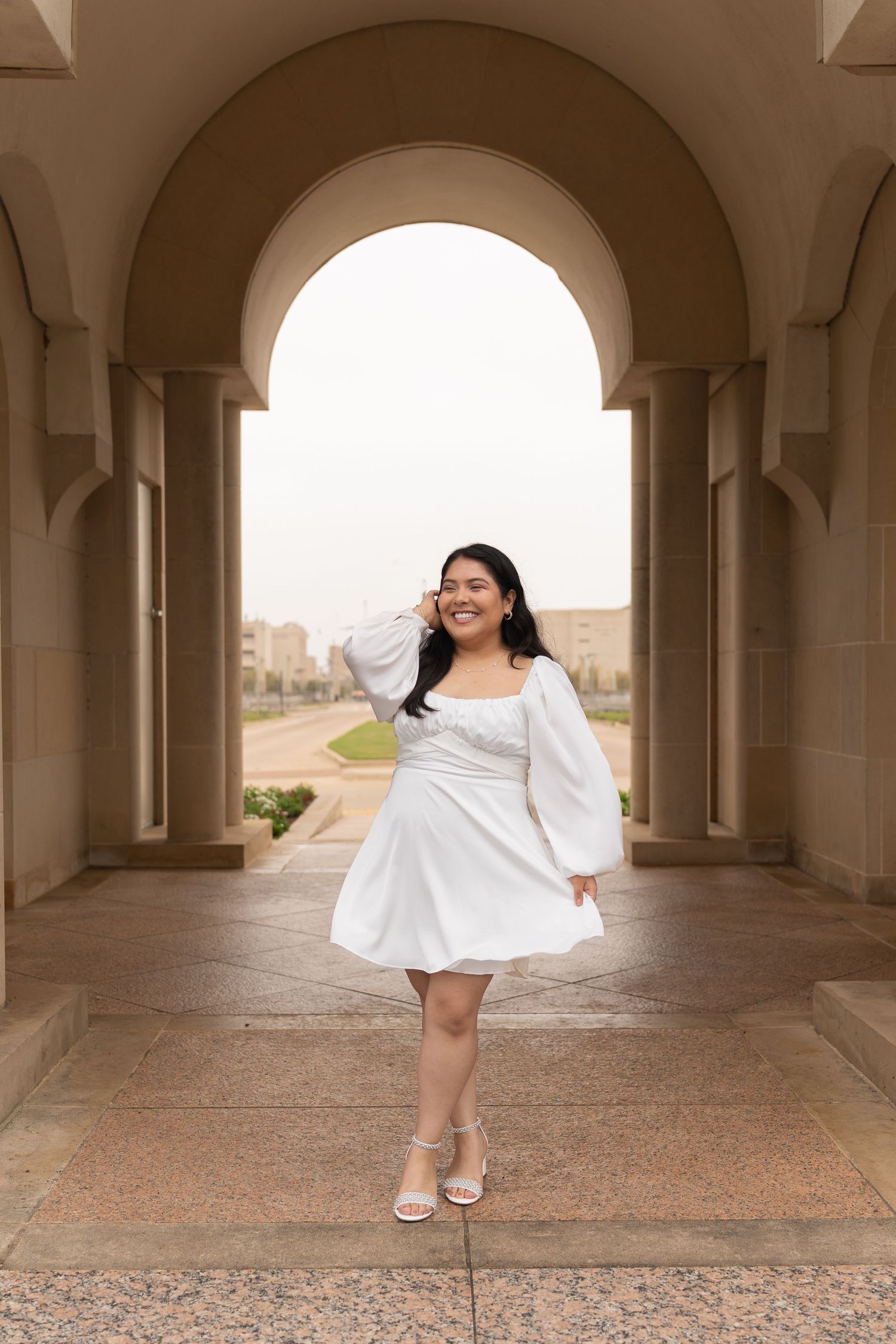 A flowing white dress twirls gracefully under an arched colonnade in a series of elegant bridal portraits.
