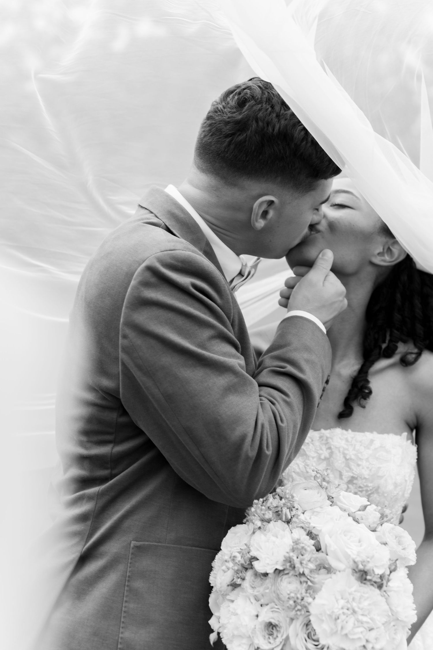 An intimate black and white wedding portrait with a white floral bouquet.
