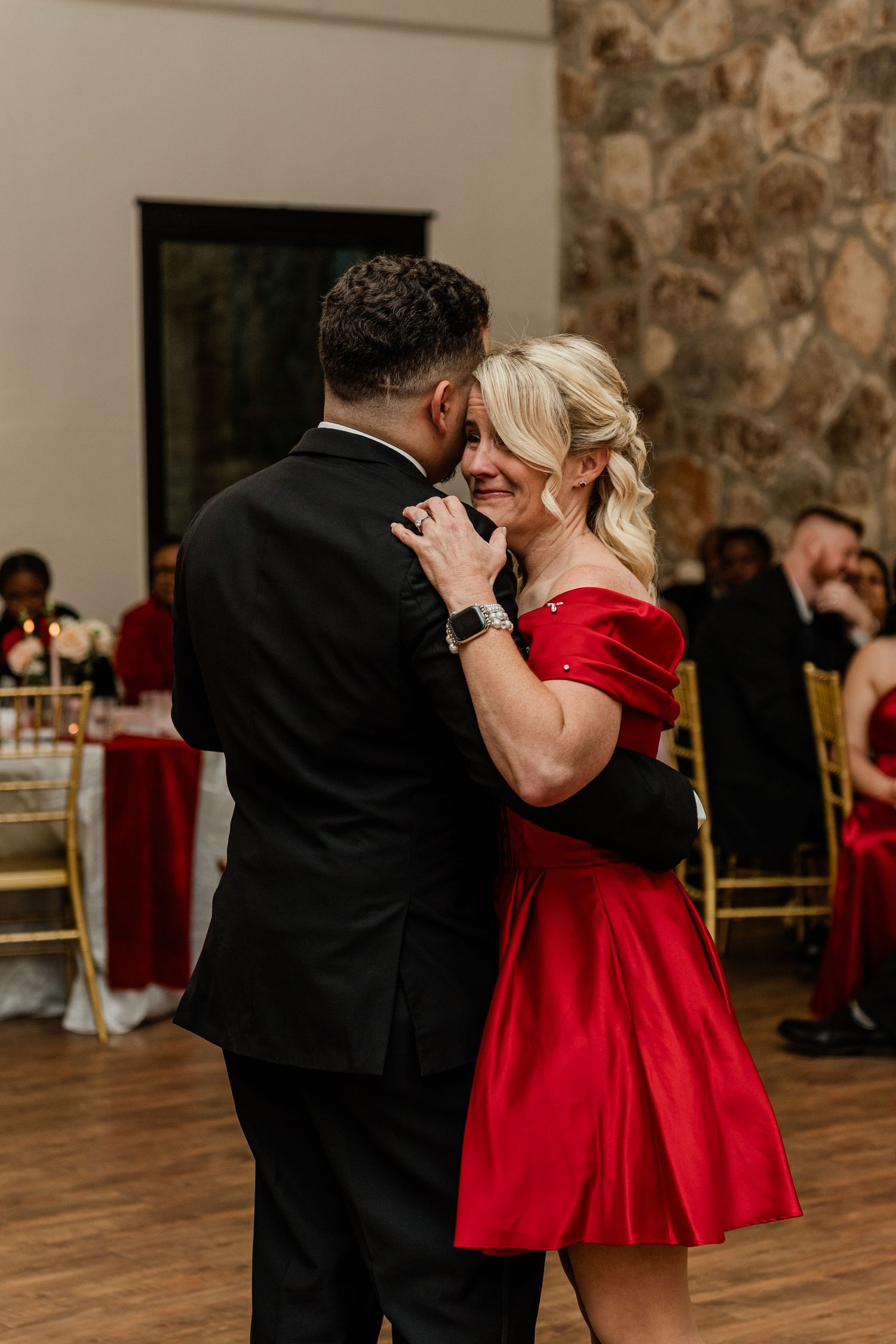 Couple dancing together in formal attire, with the woman wearing a striking red dress at an elegant venue.