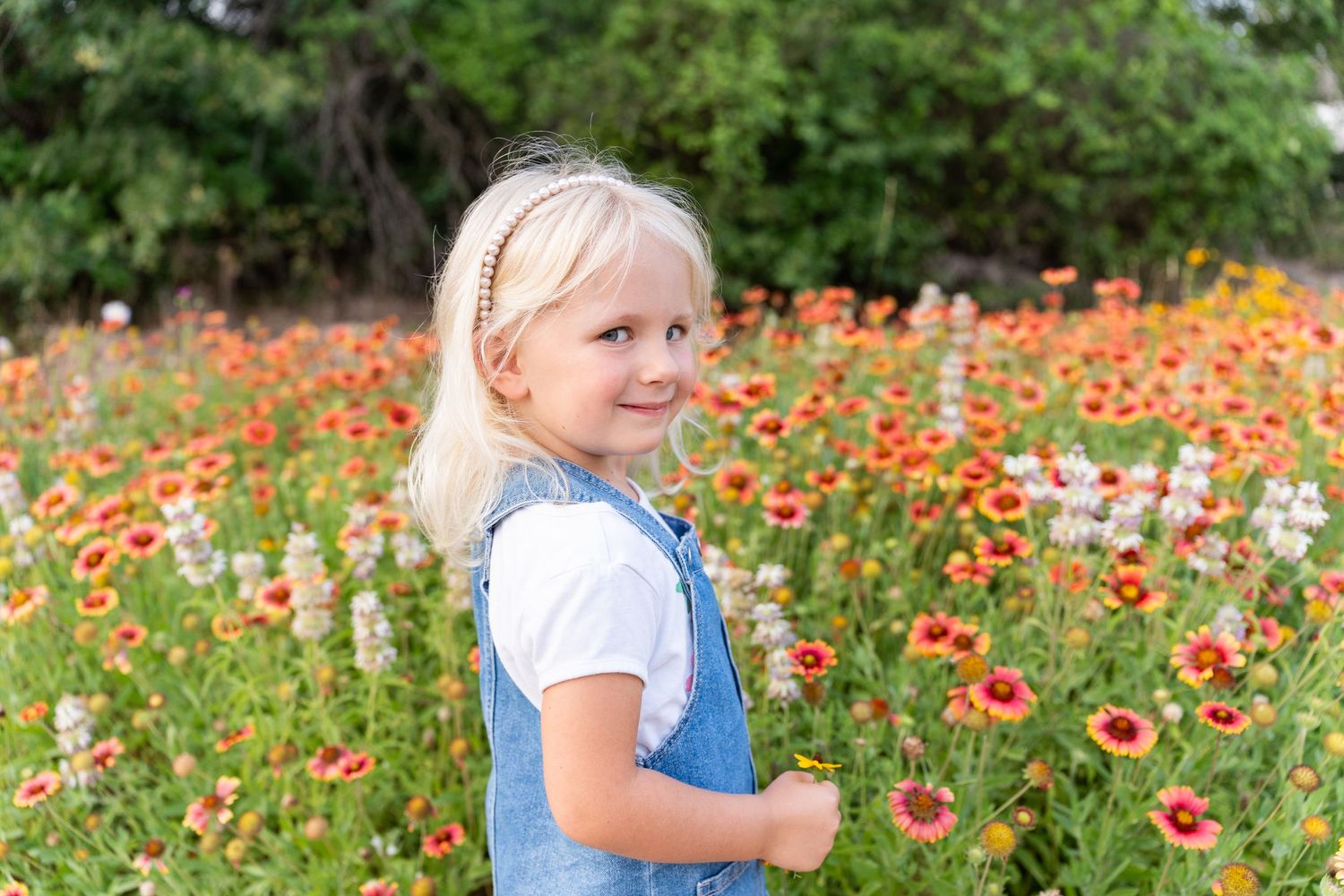 A child plays joyfully among vibrant orange and yellow wildflowers in a sunny meadow garden.