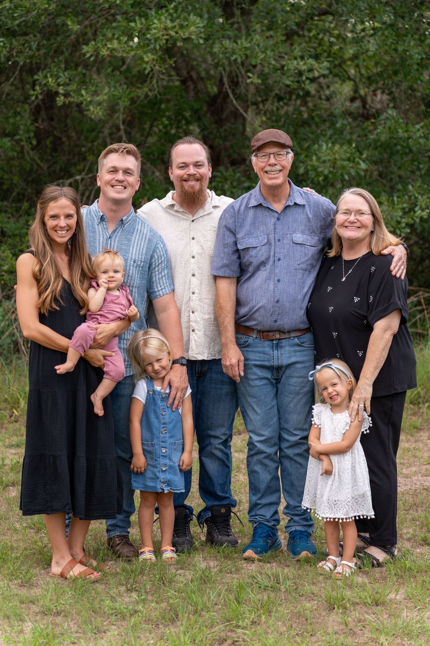 Extended family portrait outdoors with multiple generations in casual attire.