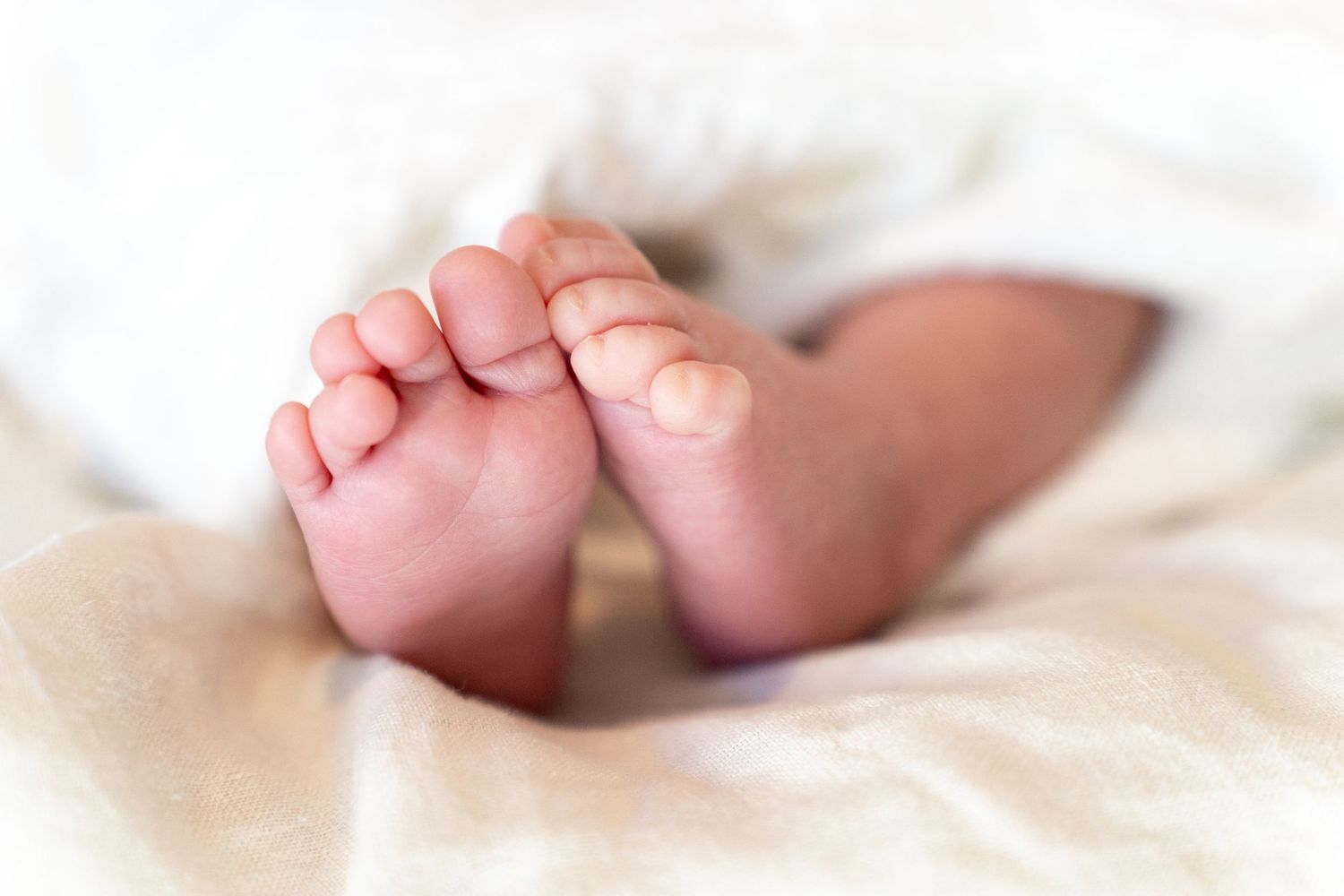 Delicate close-up series of tiny newborn baby toes on white fabric.
