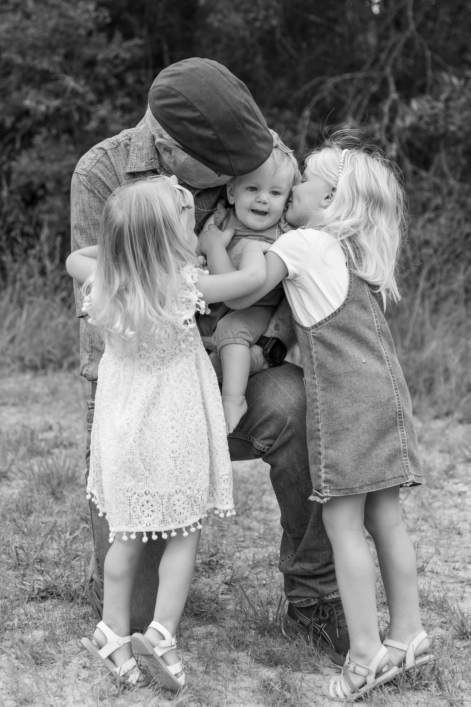 Sweet black and white photo series of toddlers in white dresses sharing innocent kisses.