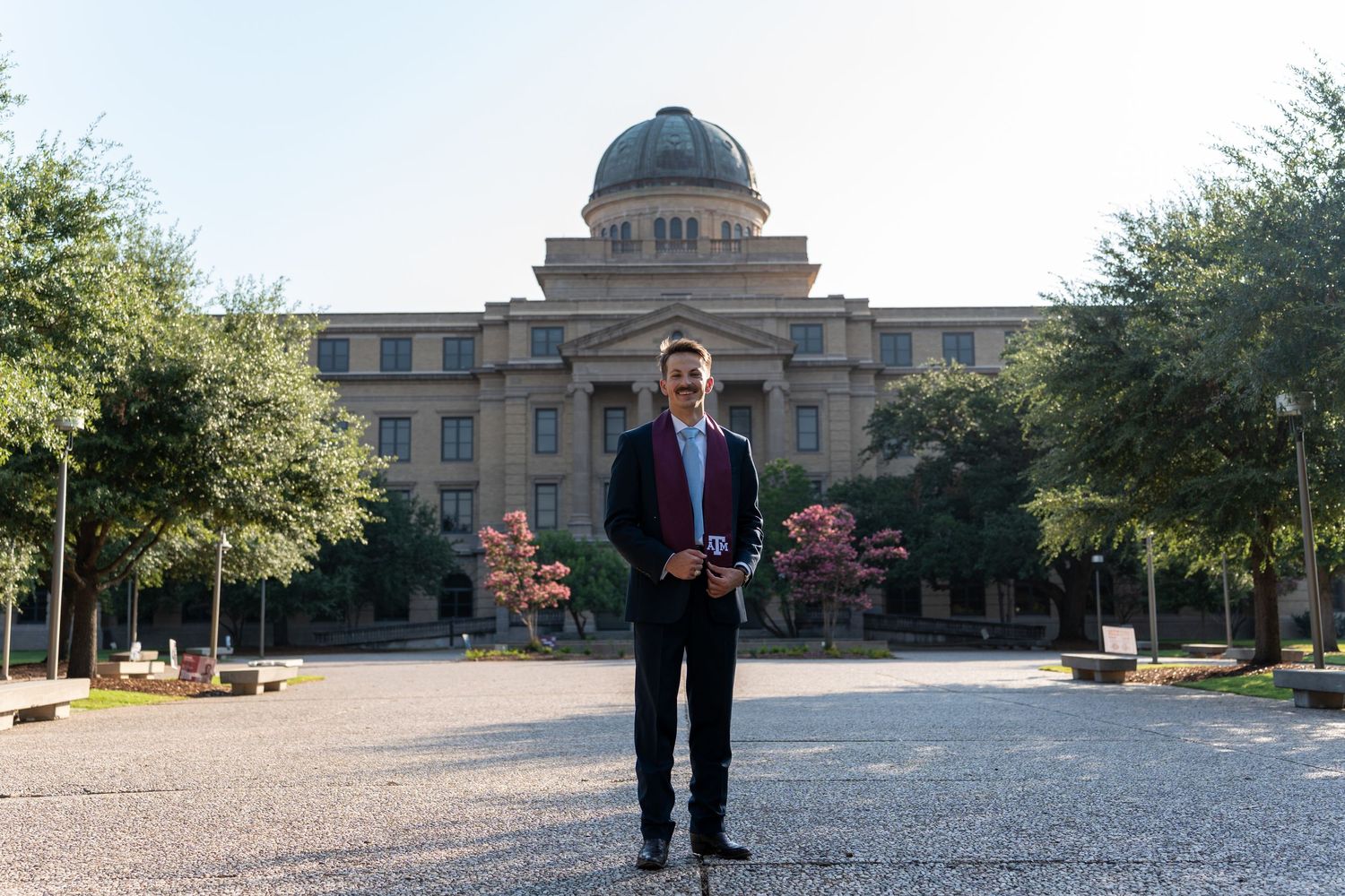 Professional portrait in front of grand academic building with domed architecture.