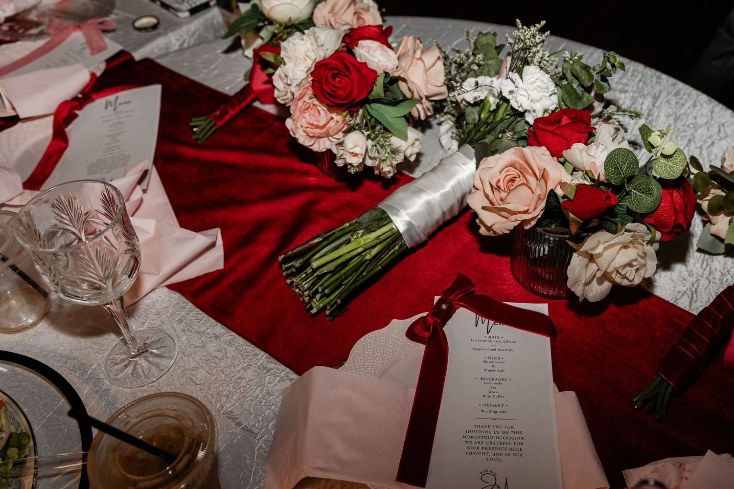 Wedding details featuring red and white floral arrangements with ribbons and invitation cards on display.