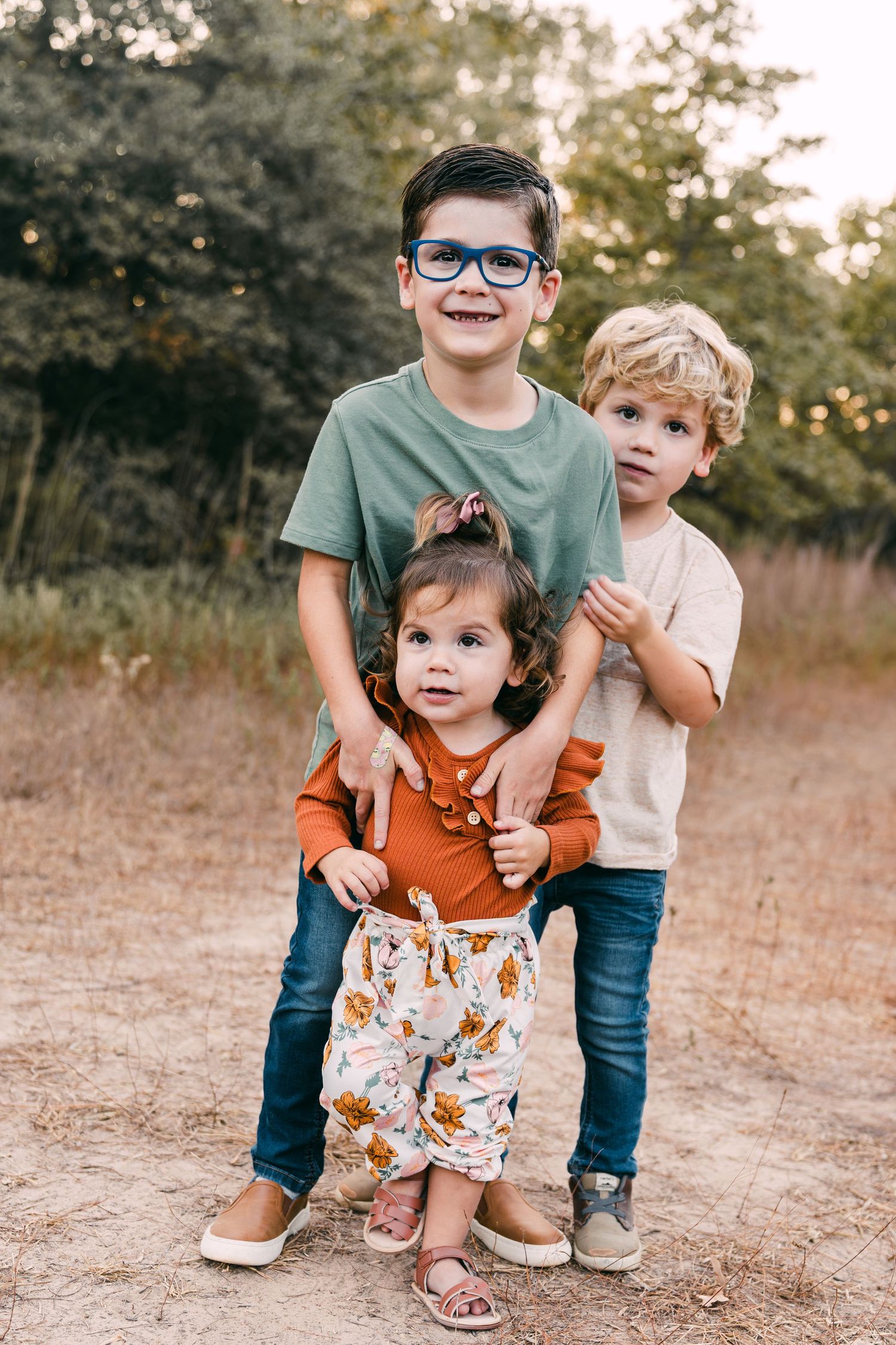 Candid moments of siblings playing together during outdoor photo session.