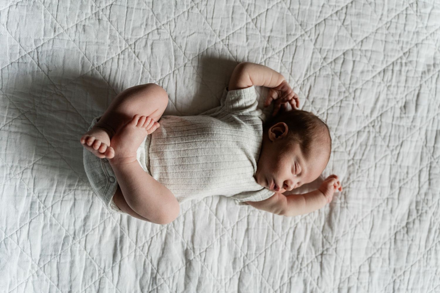 Artistic composition of newborn baby feet on white textured fabric.