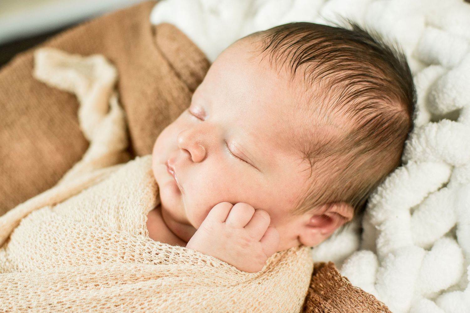 Peaceful newborn sleeping on cream colored textured blanket during photo session. San Antonio newborn photography