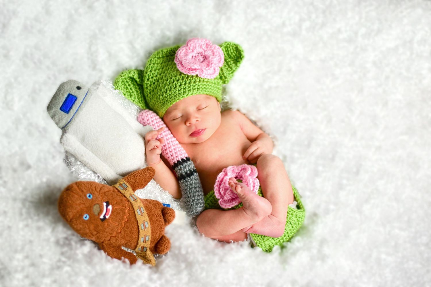 Star Wars themed photo, baby wearing green Yoda hat with pink flowers on white blanket, San Antonio newborn photography