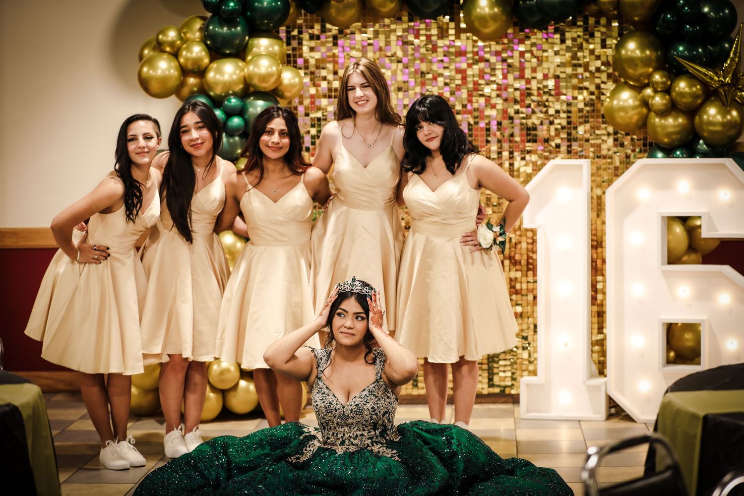 Sweet 16 party in cream-colored dresses pose for photo together against a backdrop of twinkling lights during this special Sweet 16 event.