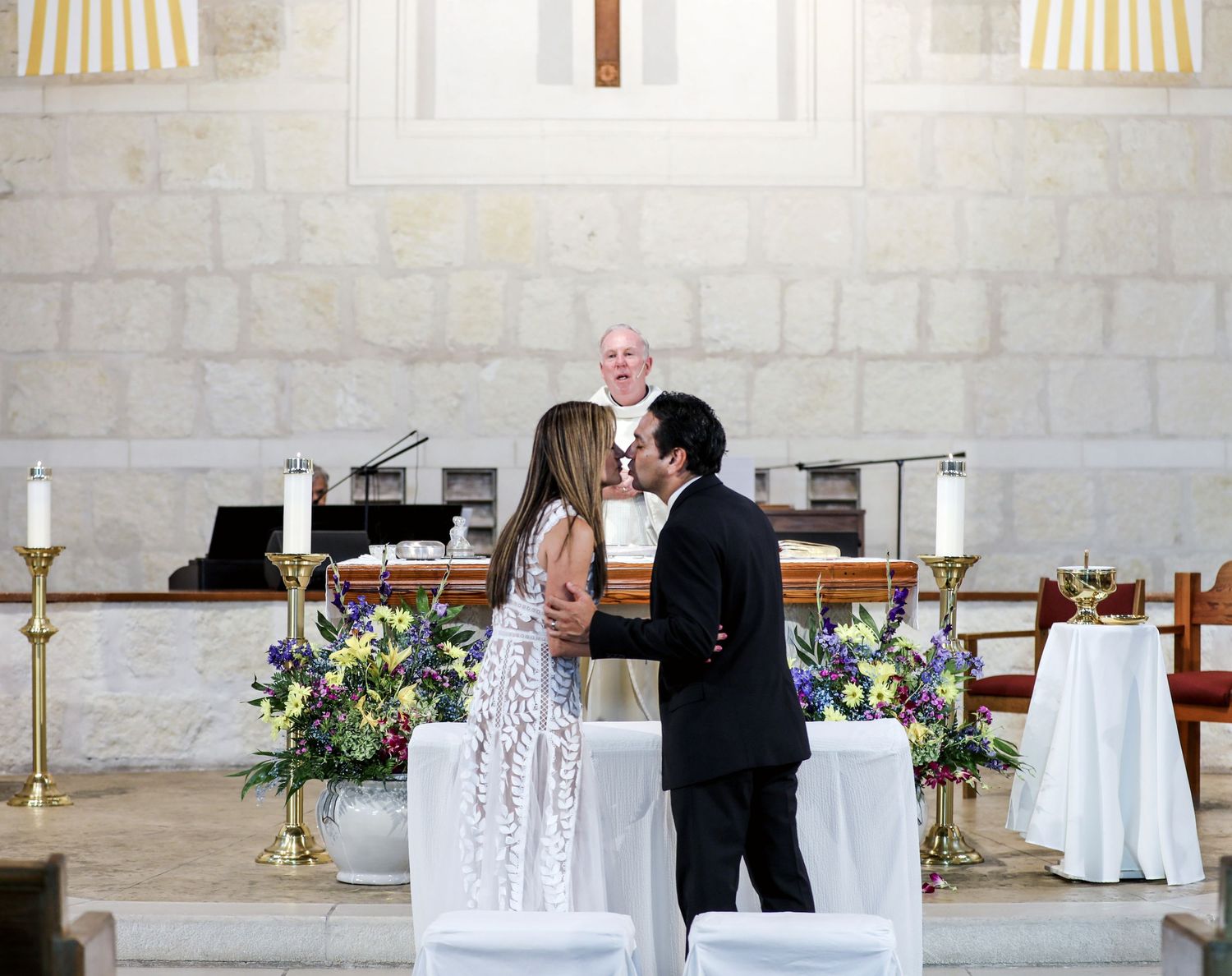 Couple sealing wedding vows with a kiss in a church setting with family, San Antonio wedding photography
