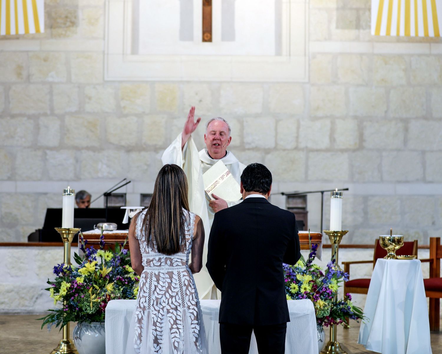Church interior decorated with yellow striped accents and floral arrangements for wedding ceremony. San Antonio wedding photography