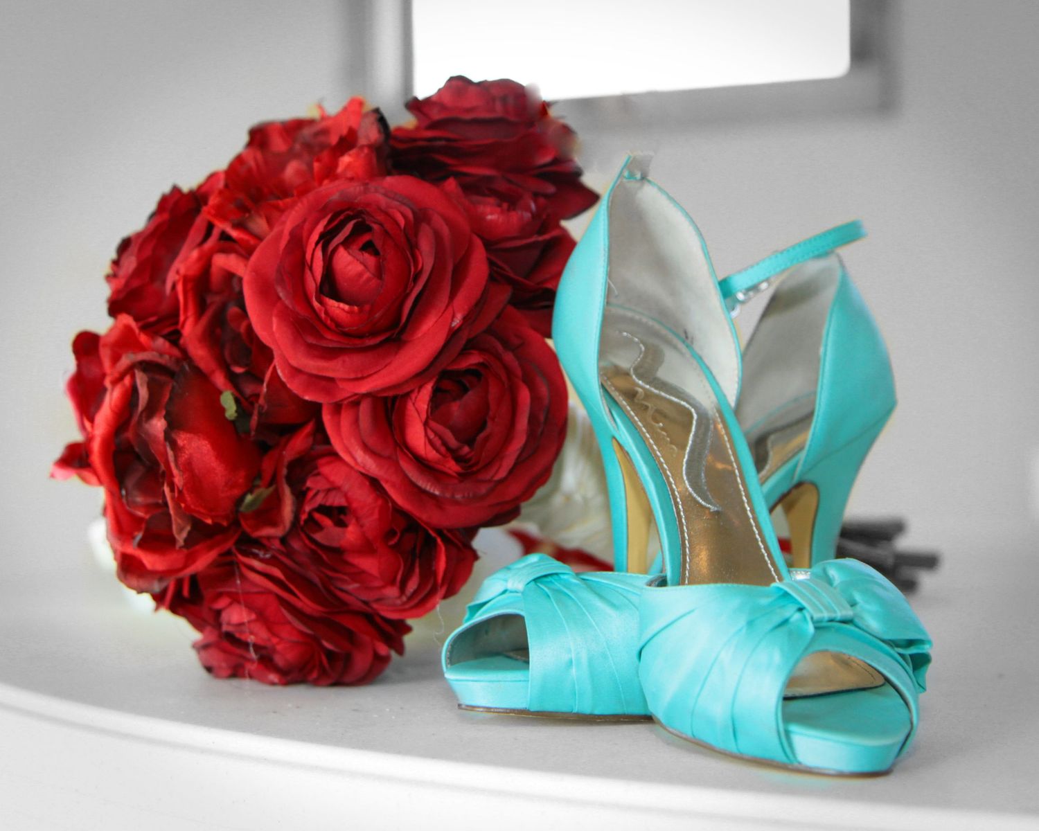 Vibrant red roses arranged beside turquoise wedding heels. San Antonio wedding photography Texas area
