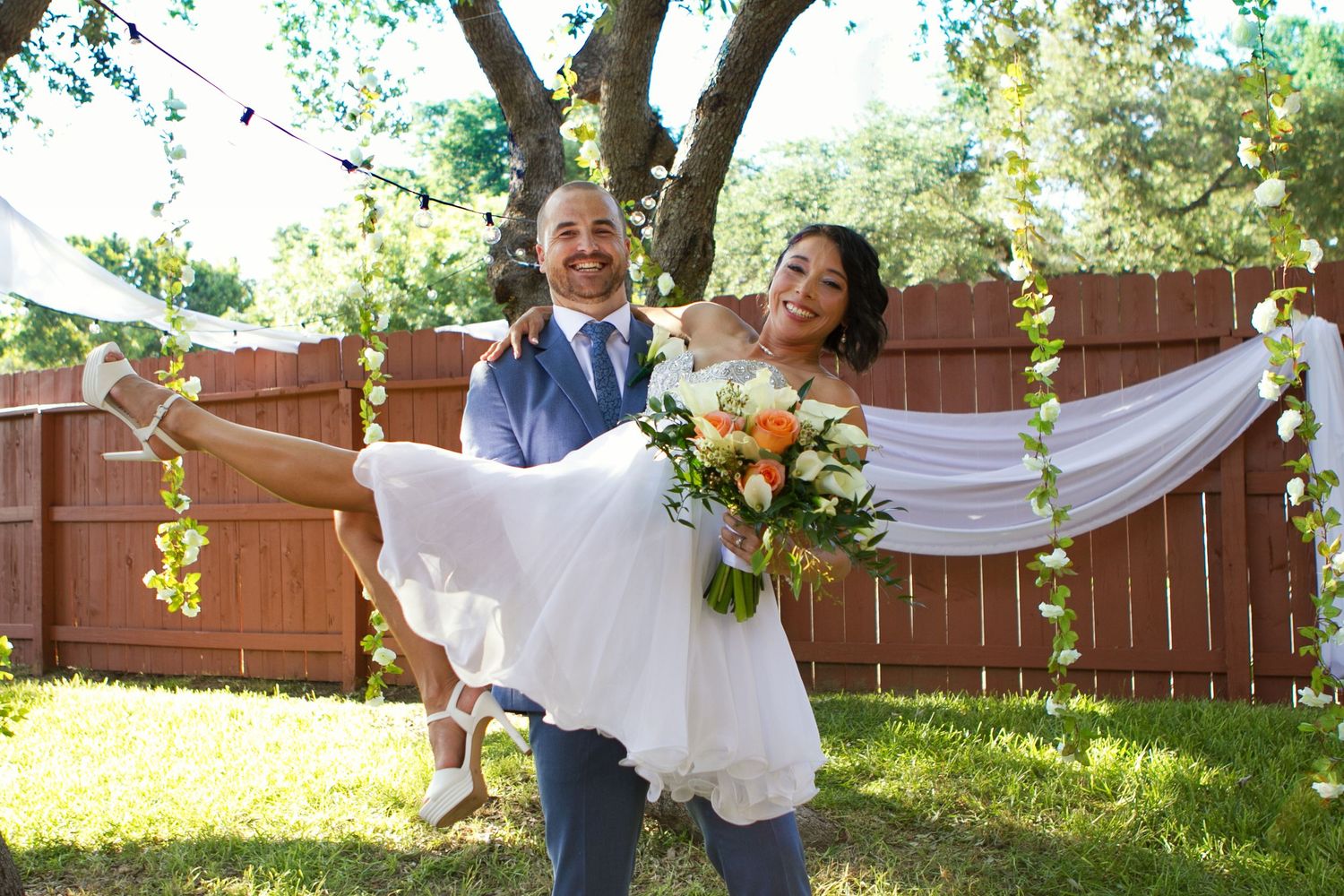 Newlyweds sharing joyful moment in outdoor garden setting with white drapery. Intimate Backyard Wedding San Antonio wedding photography
