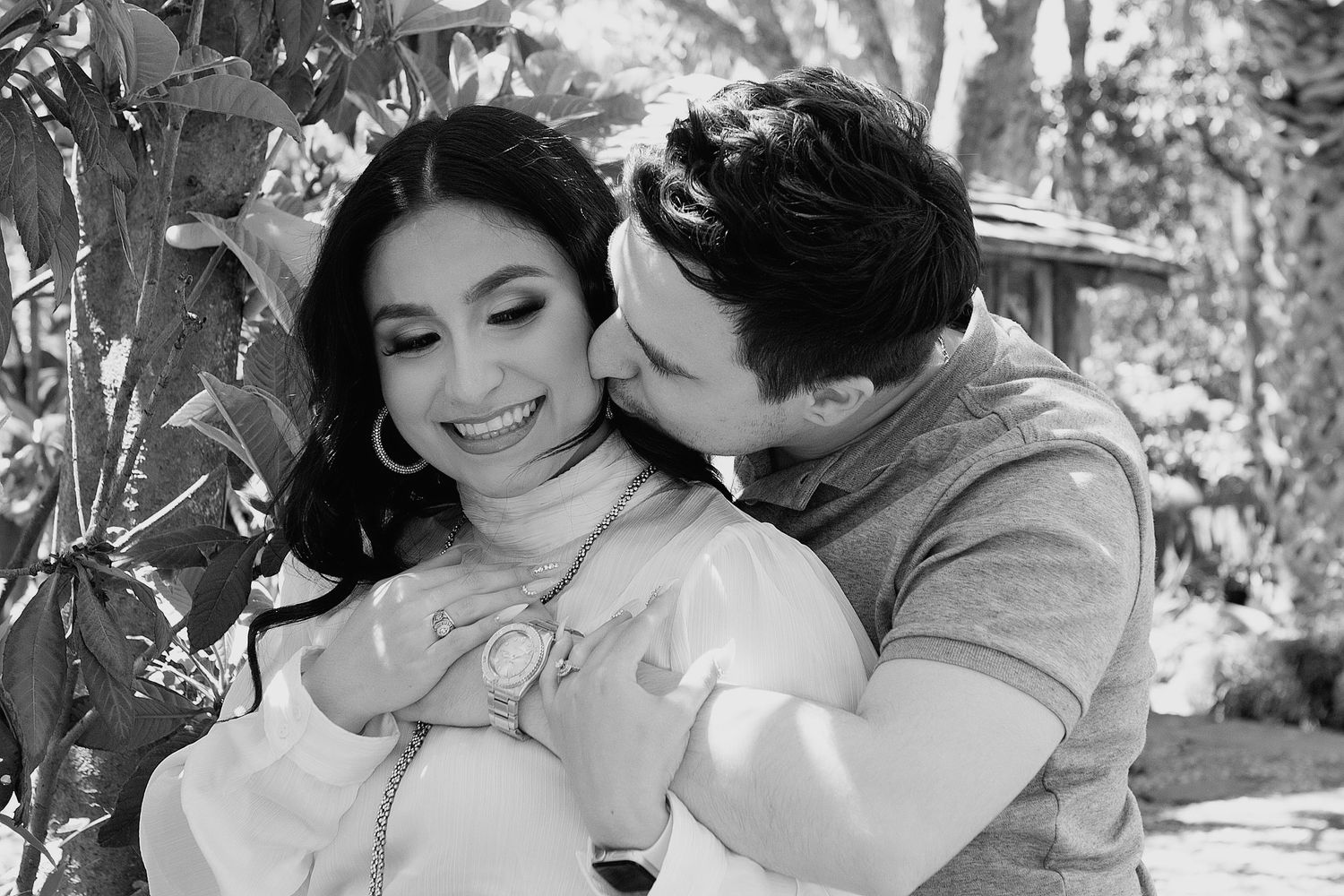 A romantic black and white photo shows a couple embracing and sharing intimate moments during engagement photography session at McNay Museum